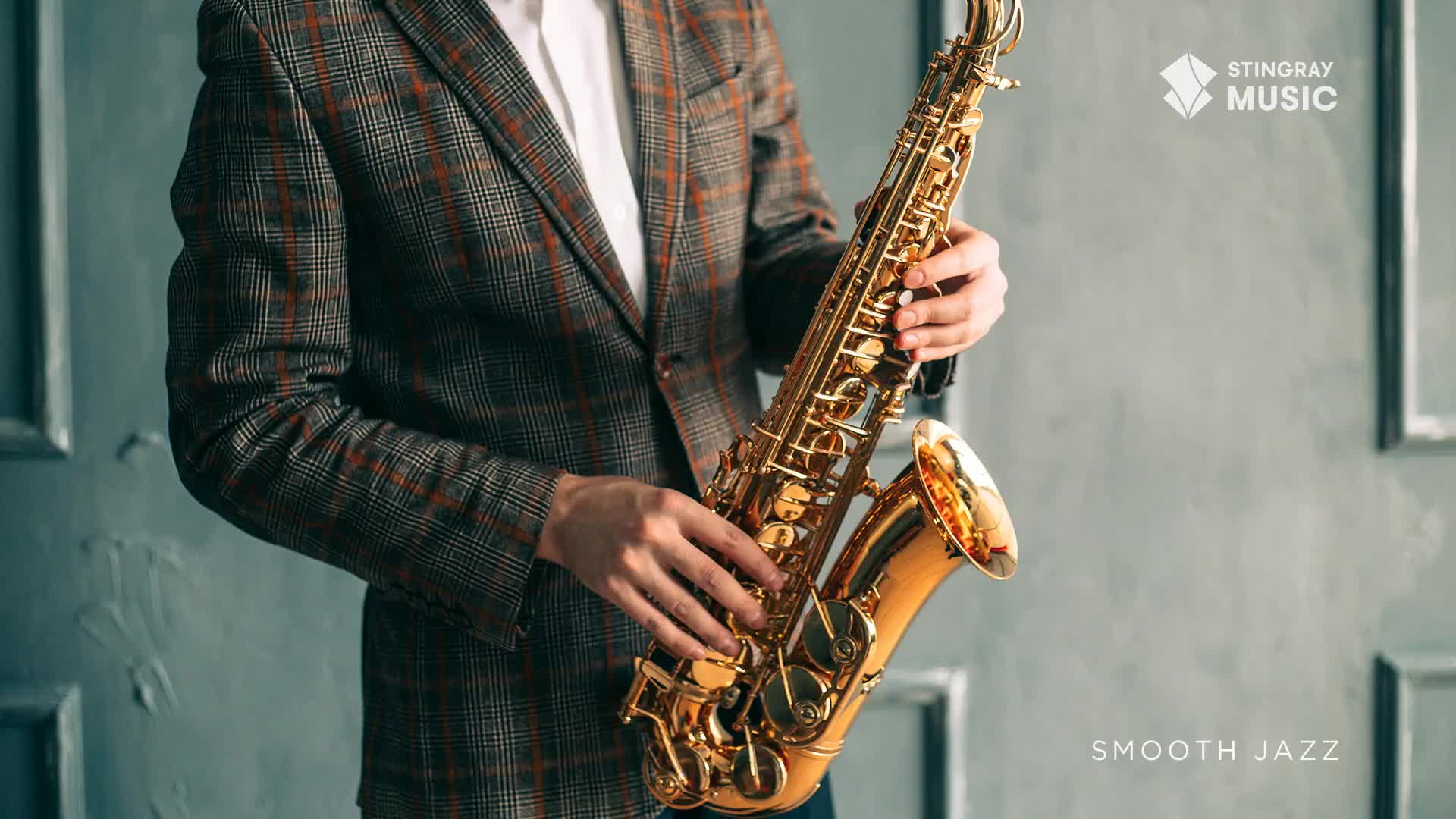 A man in a plaid jacket cradles a gleaming saxophone, his hands poised over the keys. The Stingray Smooth Jazz logo sits in the corner, hinting at the music about to be played.
