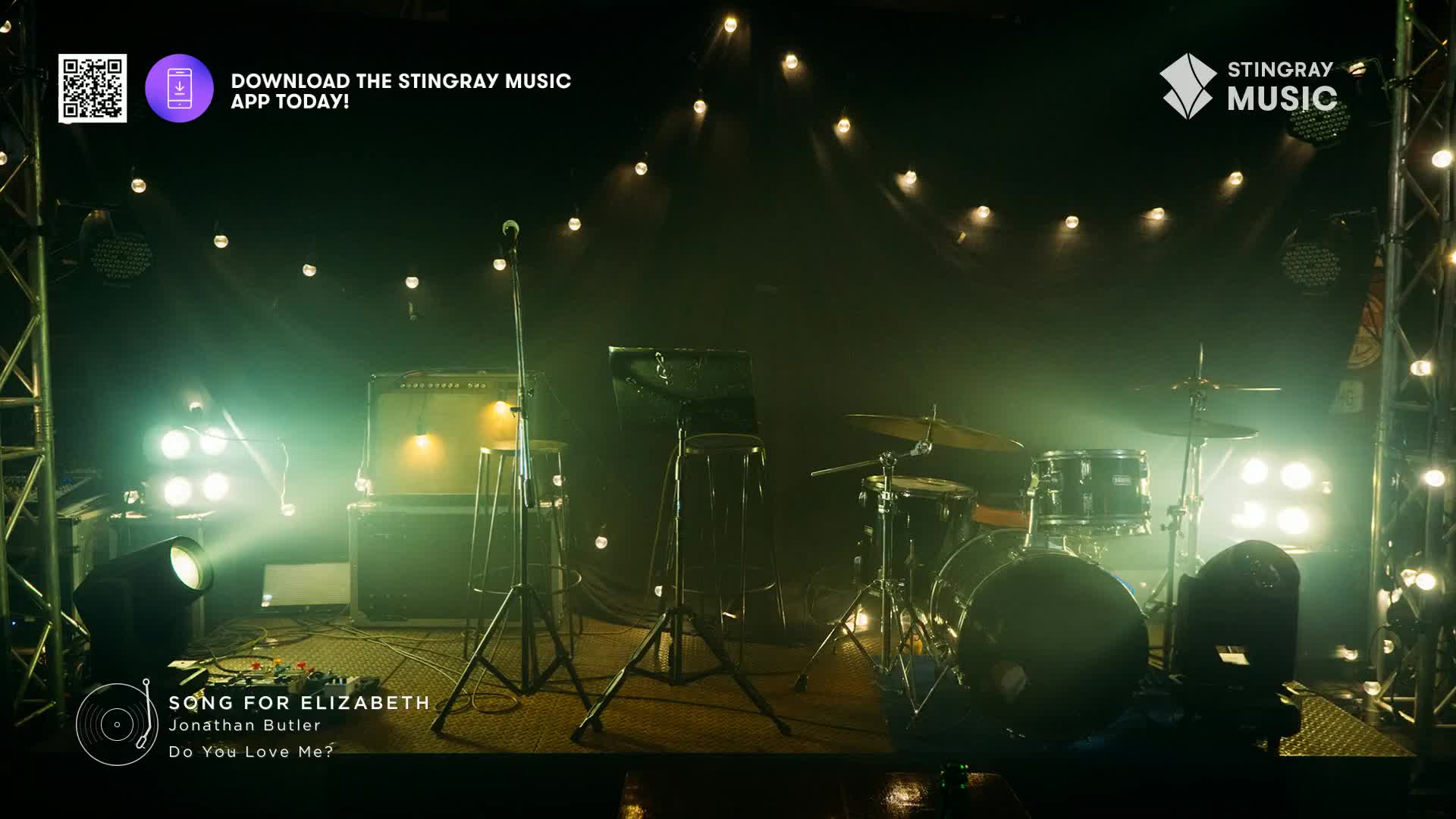 The stage is set, bathed in green light, ready for a performance from Jonathan Butler. A microphone stands ready, and the drums are in place, all under the banner of Stingray Music.
