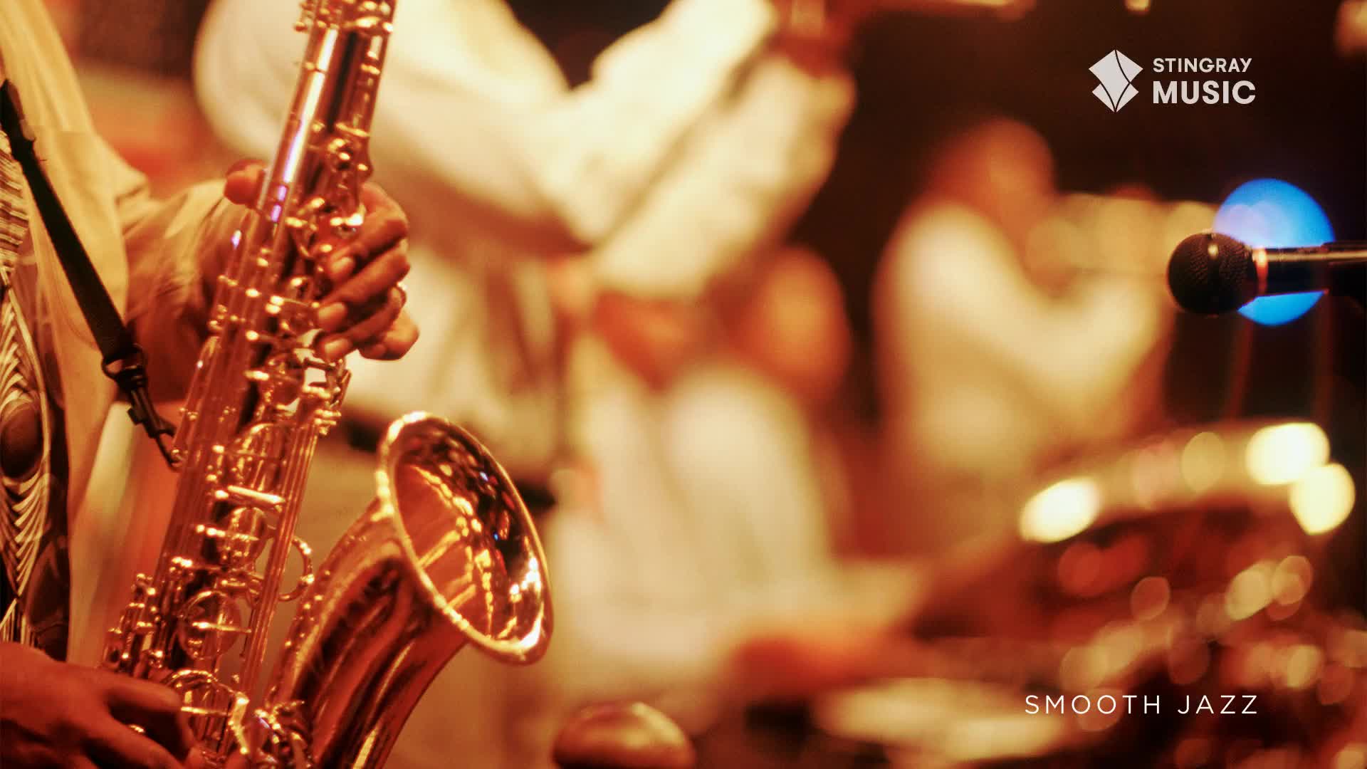 A musician's hands grip a gleaming saxophone, its brass catching the warm stage lights. Behind them, blurred figures sway to the rhythm, a quintessential Canadian smooth jazz performance.