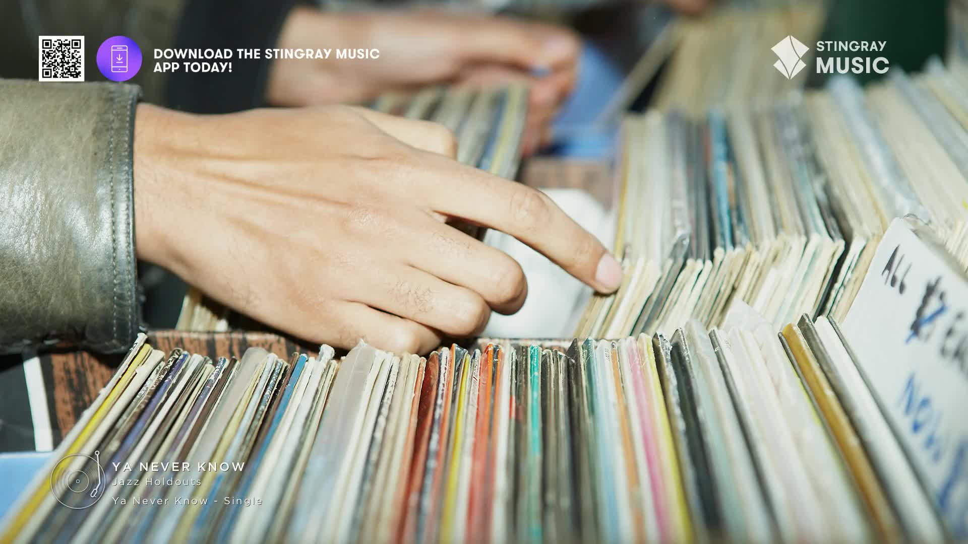 Fingers sift through rows of vinyl records, searching for a specific jazz track. The spines of the albums, a mix of faded colours and handwritten labels, stand tightly packed.
