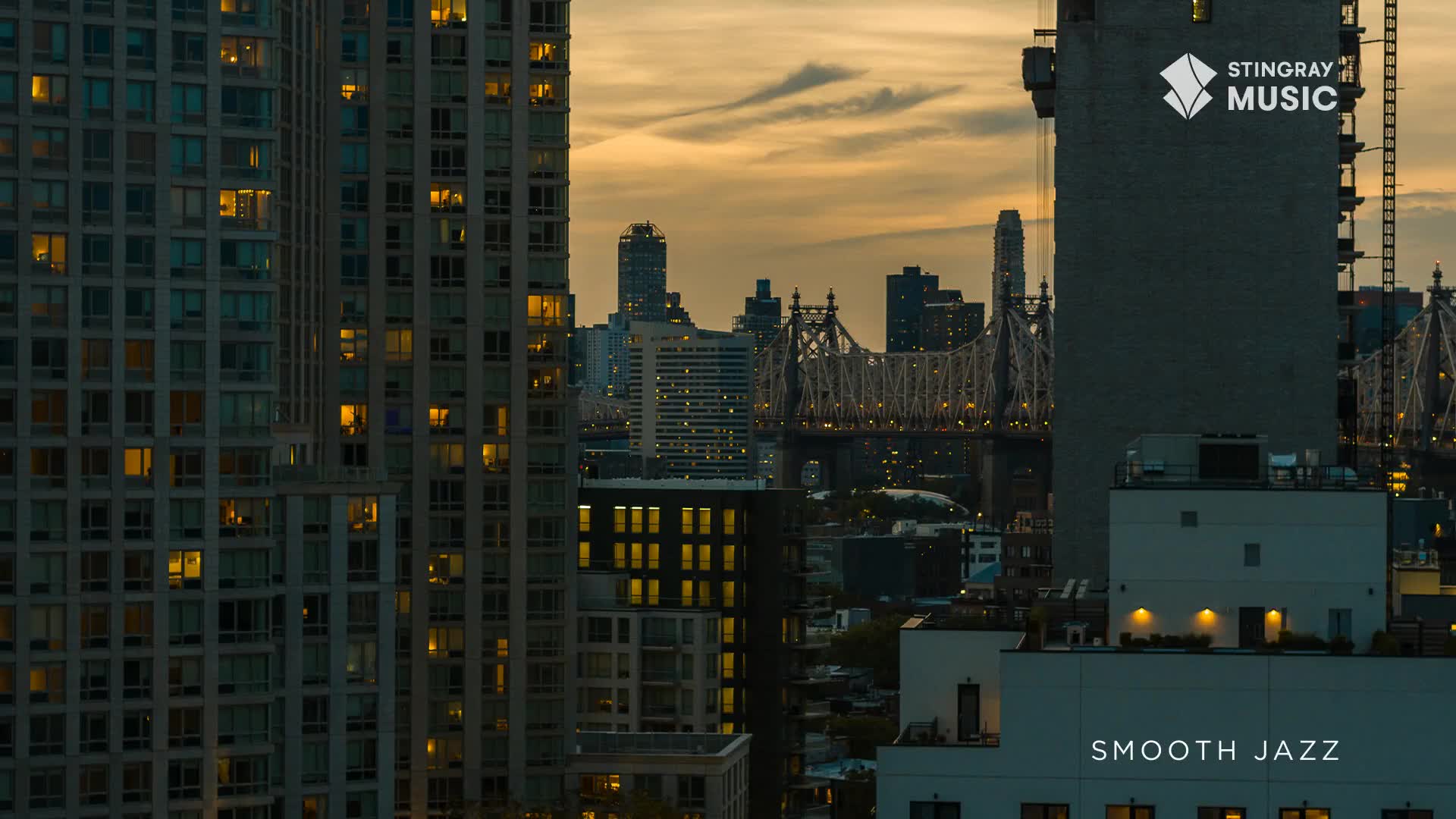The sky above the city glows a warm orange as dusk settles. Lights begin to twinkle in the windows of the tall buildings, a familiar sight in Canada.