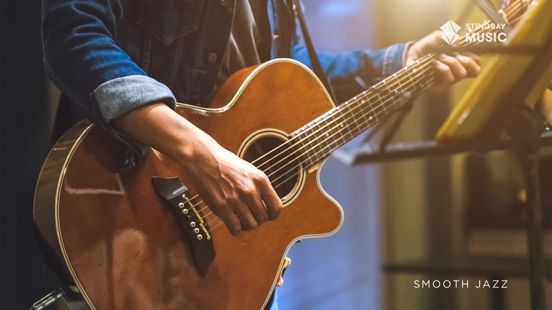Fingers dance across the fretboard of a sunburst acoustic guitar. The smooth jazz melody fills the air as the musician's hands move with practiced ease.