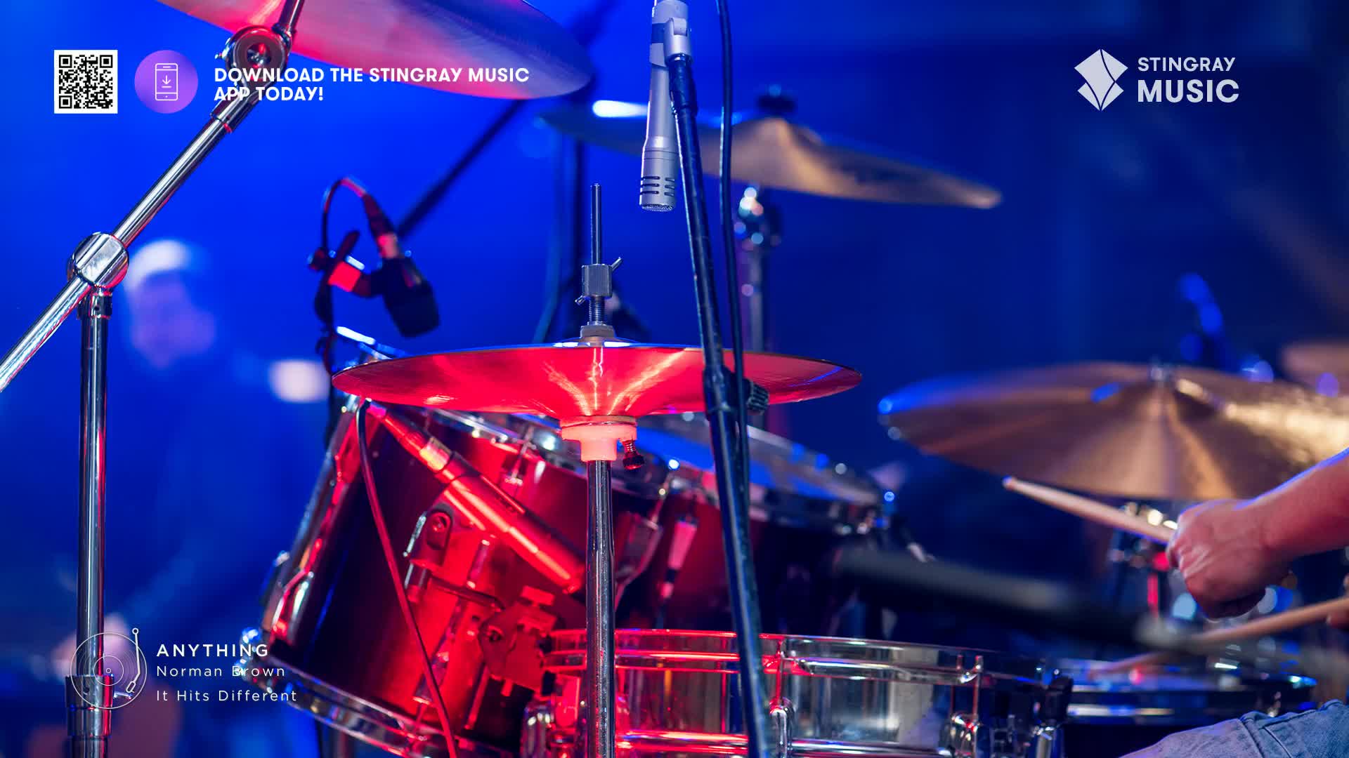Drumsticks strike a cymbal, sending a shimmer of light across the stage. The deep red of the snare drum catches the spotlight as the rhythm section lays down a groove for Norman Brown's smooth jazz set.