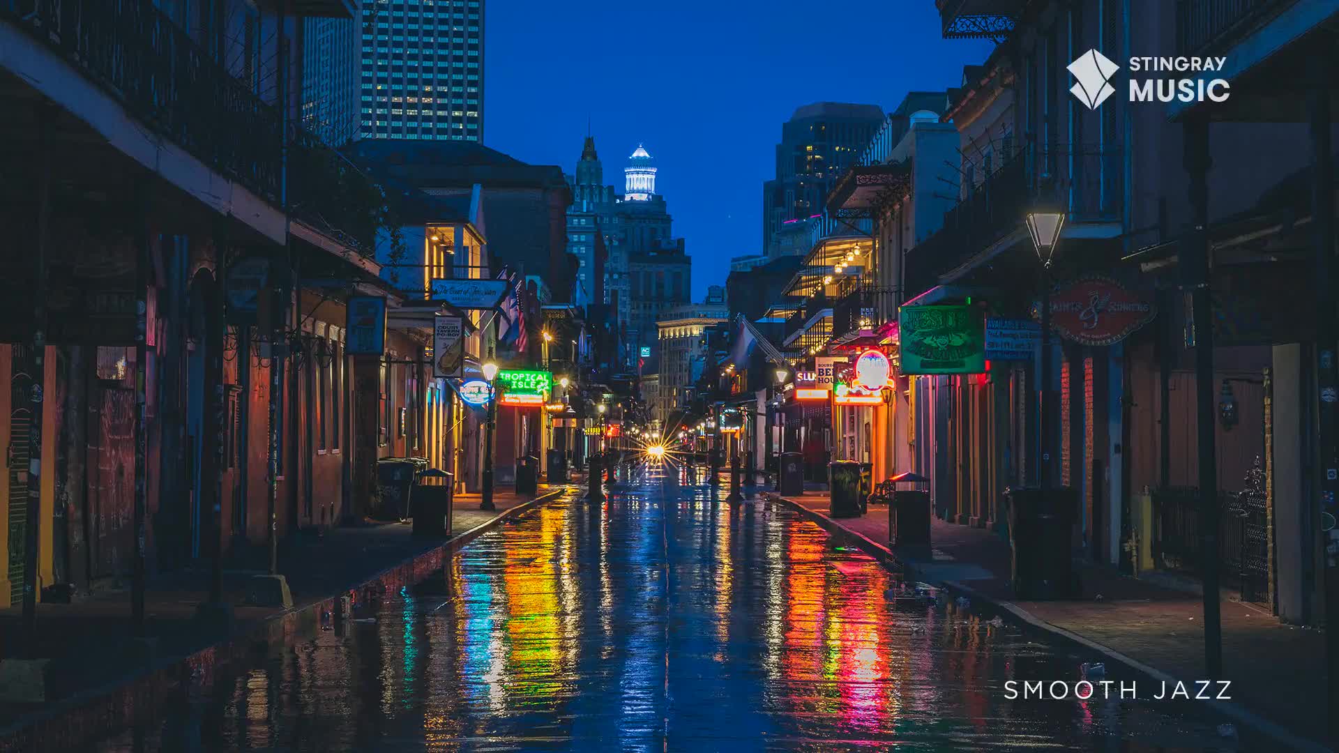 A car's headlights cut through the twilight on a wet street, reflecting neon signs from the shops lining the narrow lane. The air feels thick with the promise of a warm evening, like a slow jazz melody drifting from a distant club.