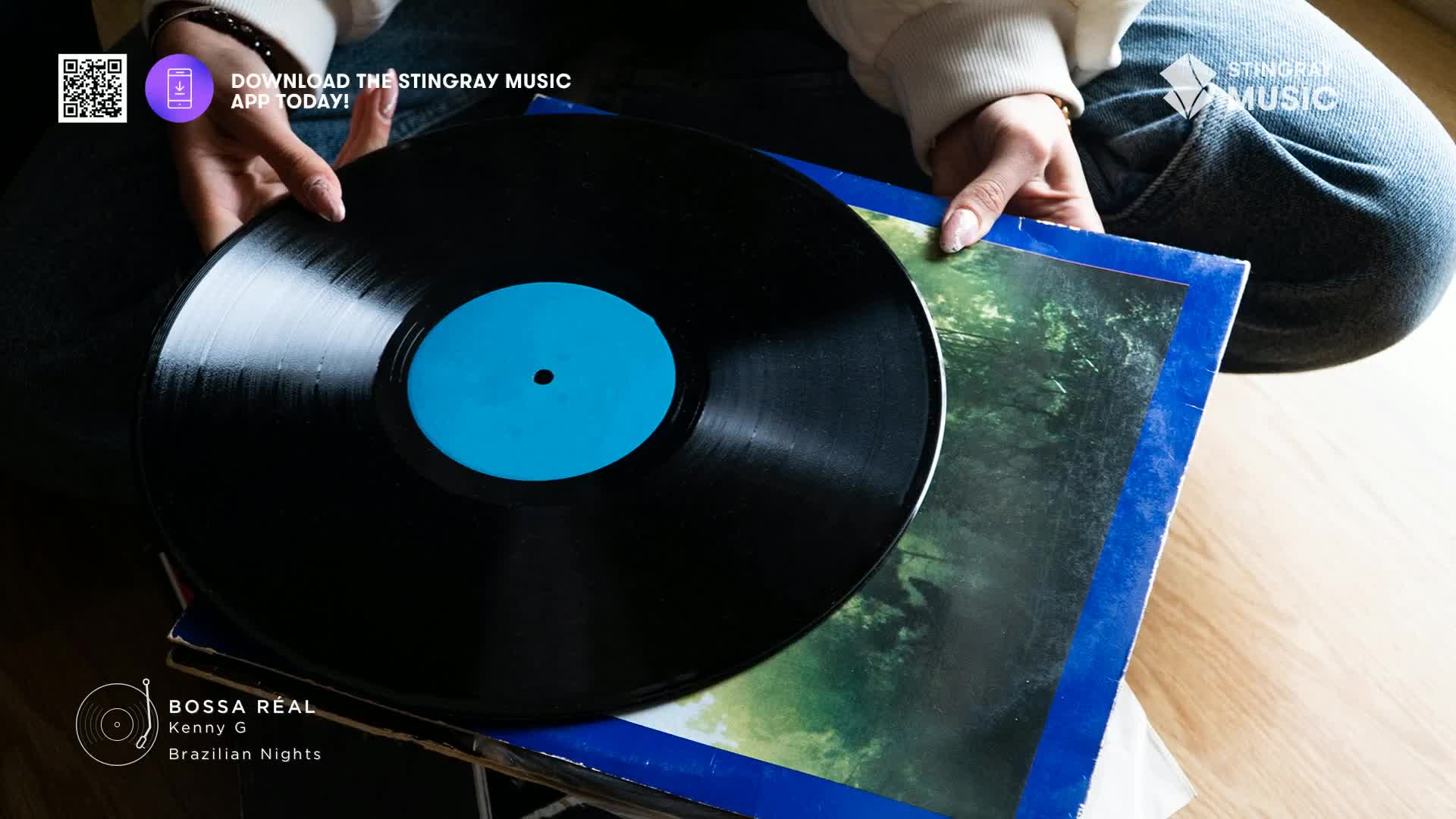 Fingers carefully lift a large black vinyl record, its blue label catching the light. It rests atop a stack of album covers, hinting at a collection of smooth jazz. Fingers carefully lift a large black vinyl record, its blue label catching the light. It rests atop a stack of album covers, hinting at a collection of smooth jazz.