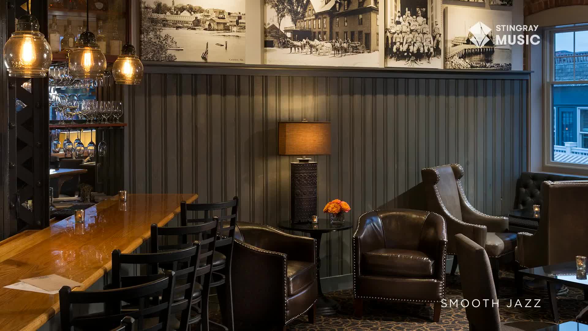 The warm glow of pendant lights illuminates a polished wood bar. Plush leather chairs invite patrons to relax in this cozy Canadian lounge. The warm glow of pendant lights illuminates a polished wood bar. Plush leather chairs invite patrons to relax in this cozy Canadian lounge.