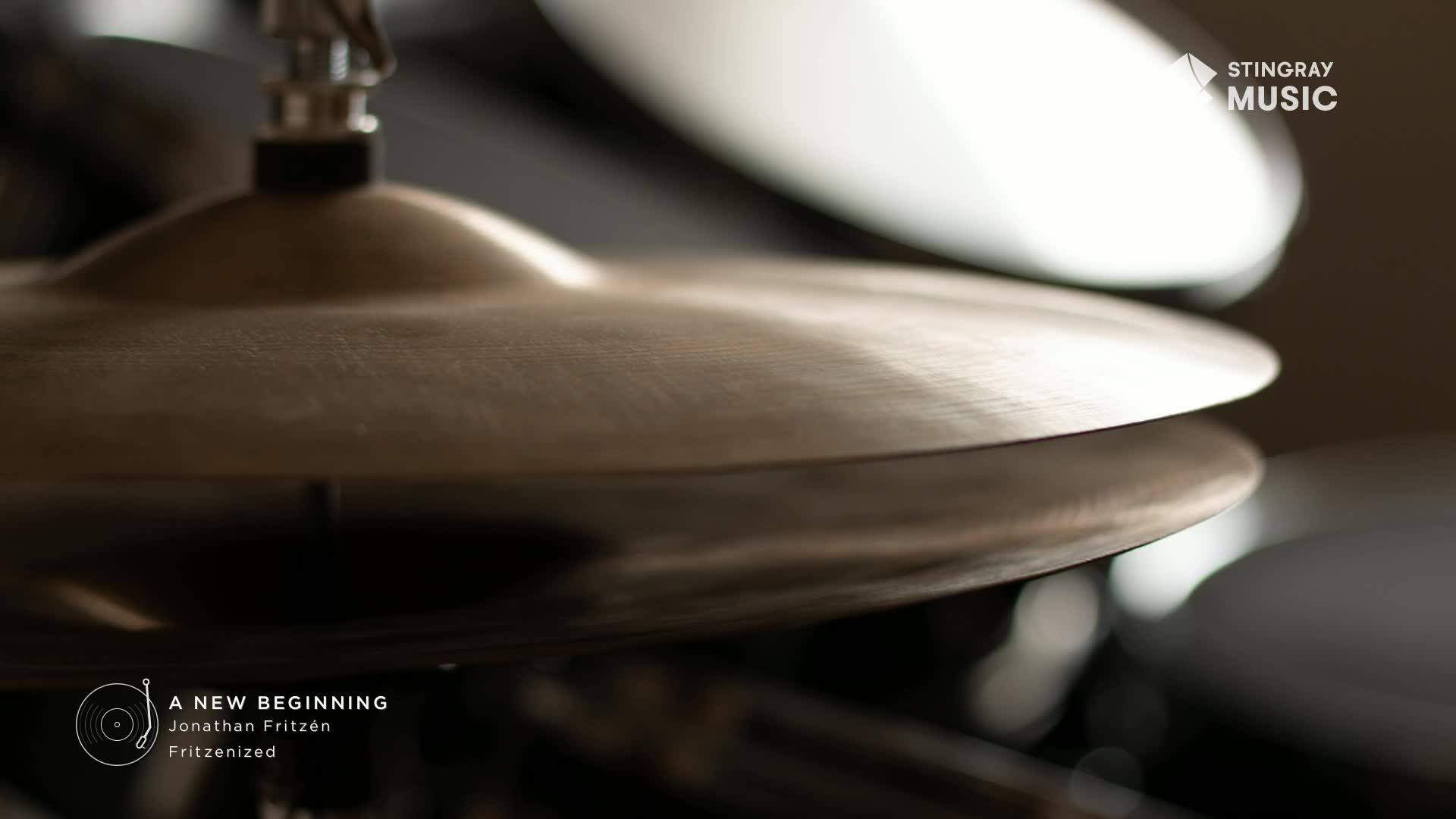 A drumstick hovers just above a brass cymbal, ready to strike. The Stingray Music logo is visible in the upper right corner.