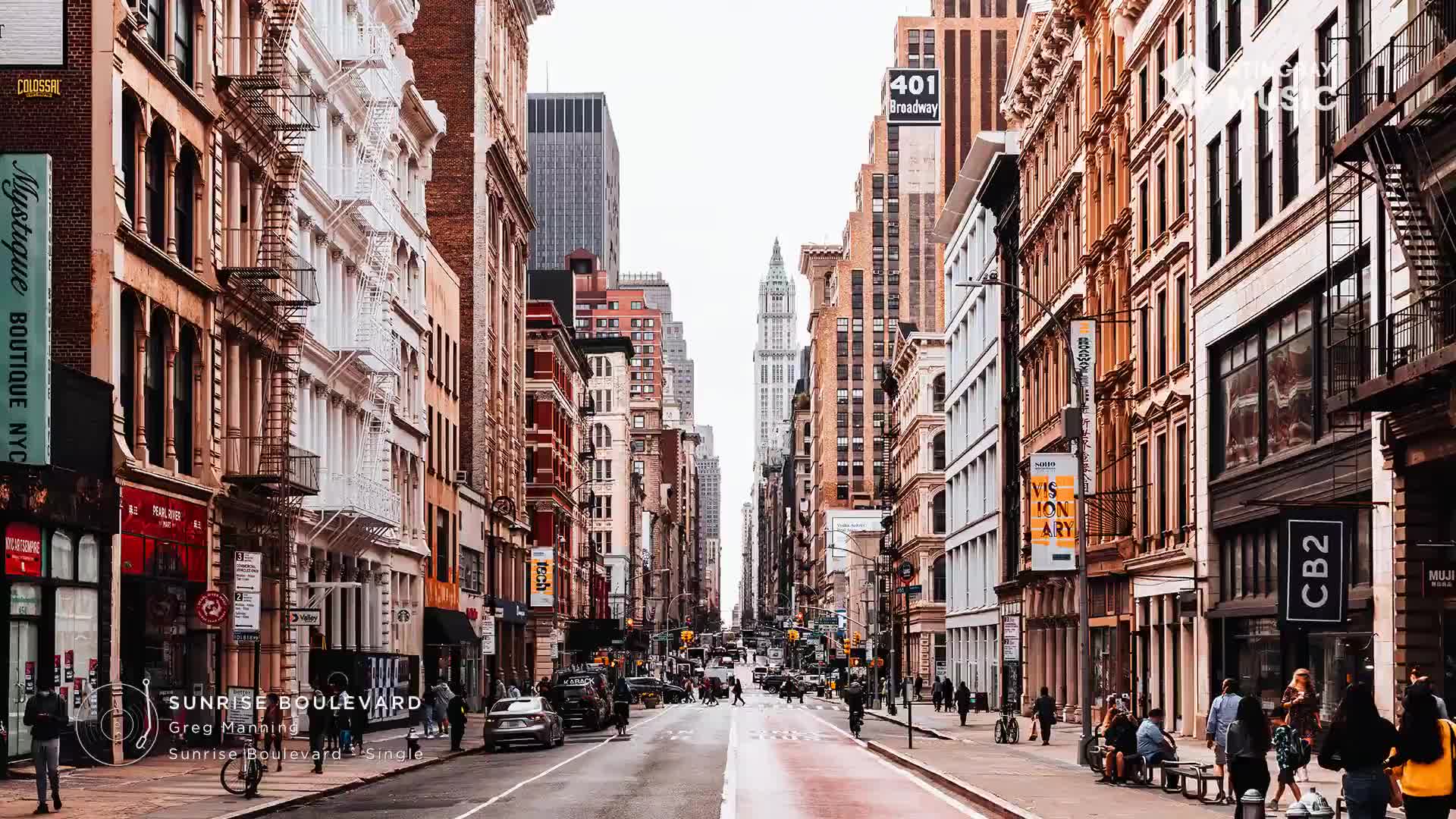 Cars move down the street, their headlights catching the warm brick buildings. People stroll along the sidewalks, some pausing to look in shop windows.