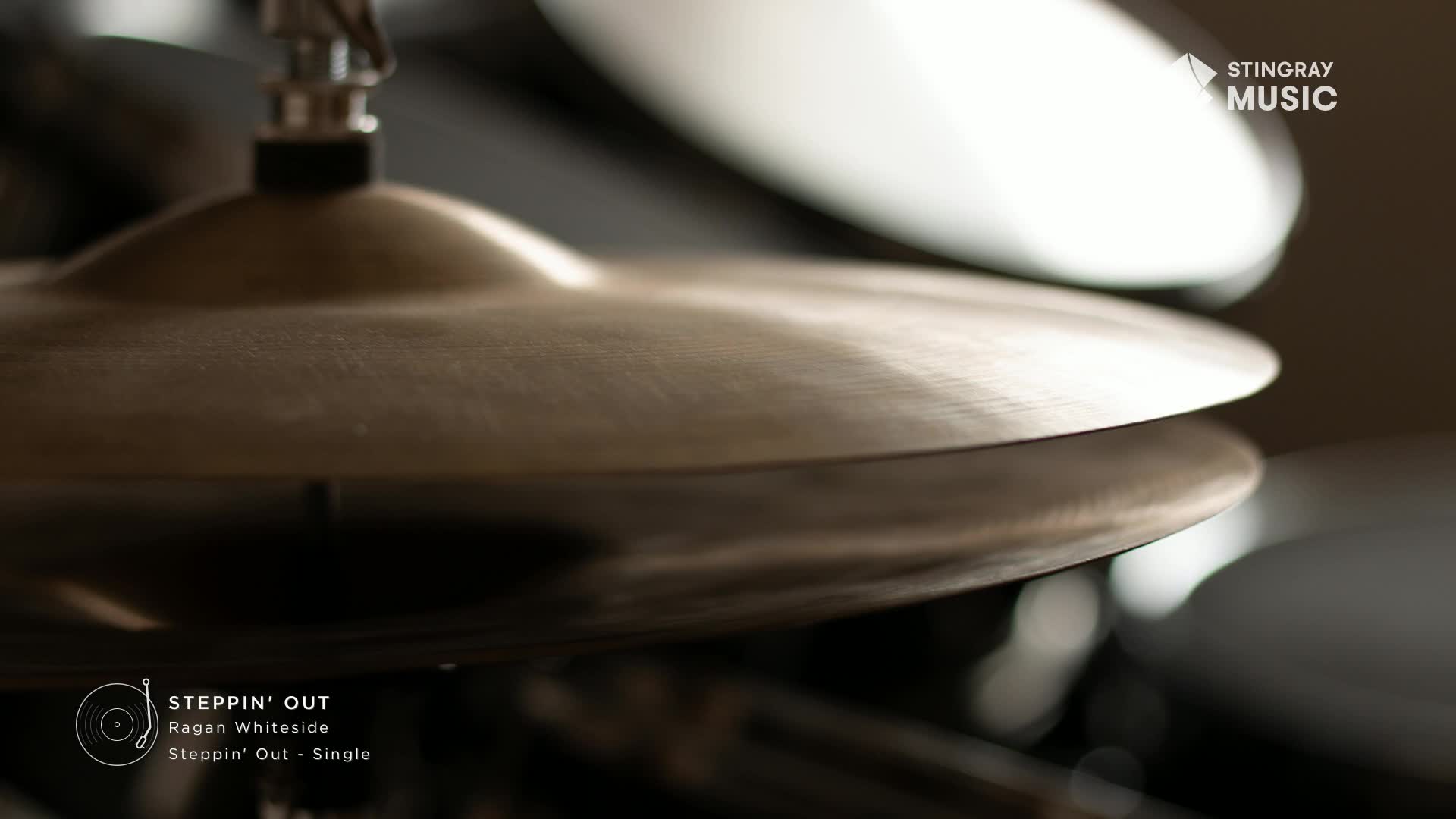 A drumstick is about to strike the shimmering cymbals, ready to unleash the smooth jazz of Ragan Whiteside's "Steppin' Out" single. The metallic sheen catches the light, hinting at the crisp sound that will soon fill the air.