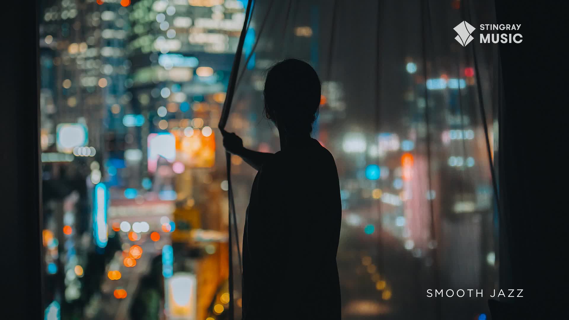 The city lights of Toronto glow through the sheer curtain as a person reaches out. The smooth jazz soundtrack of Stingray Music plays softly.