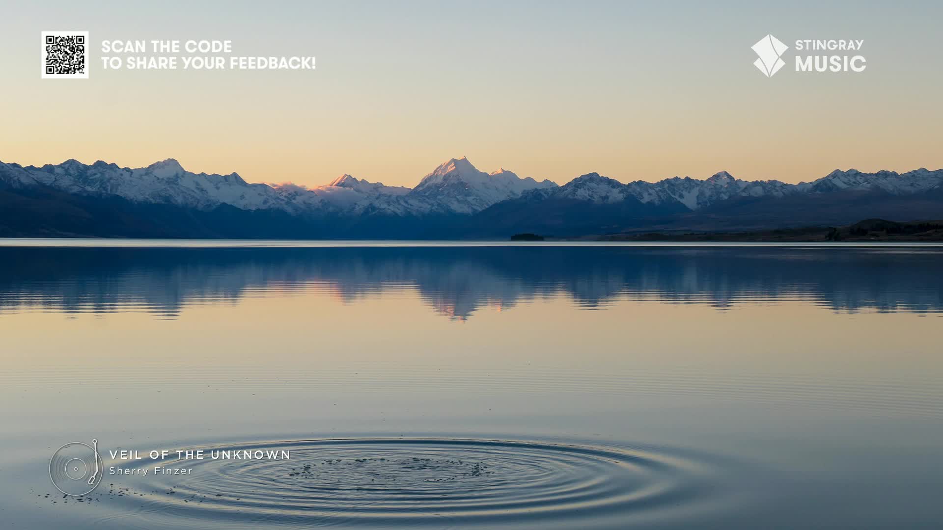 A small splash disturbs the glassy lake, sending concentric ripples outward. Snow-capped mountains, reflected in the water, are a backdrop to the scene, which could easily be used by Stingray The Spa in Canada for relaxation.
