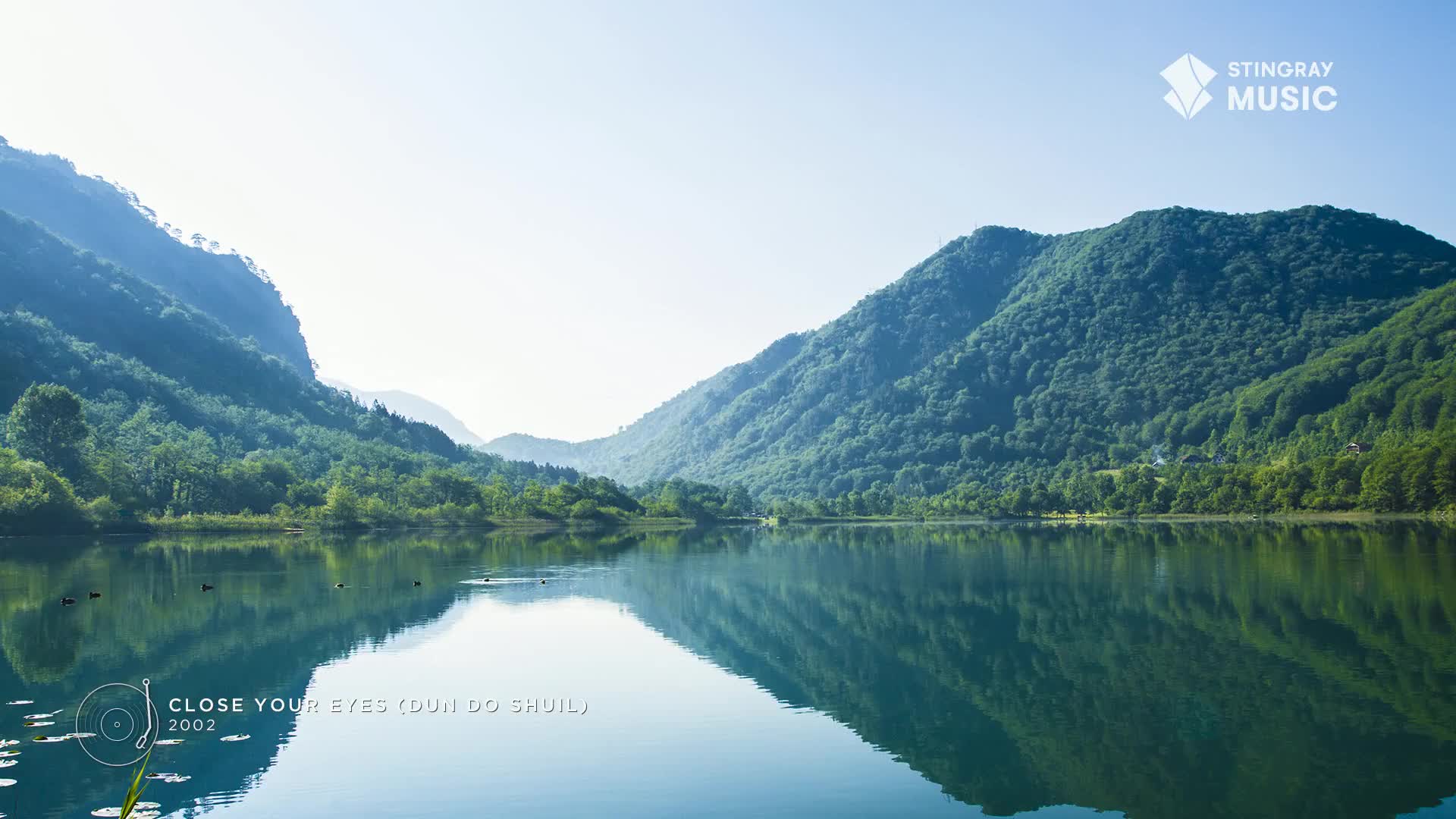 Across the still water, the green mountains are perfectly mirrored. The sky is bright, and the air is crisp, perfect for a relaxing day at a spa in Canada, like Stingray.
