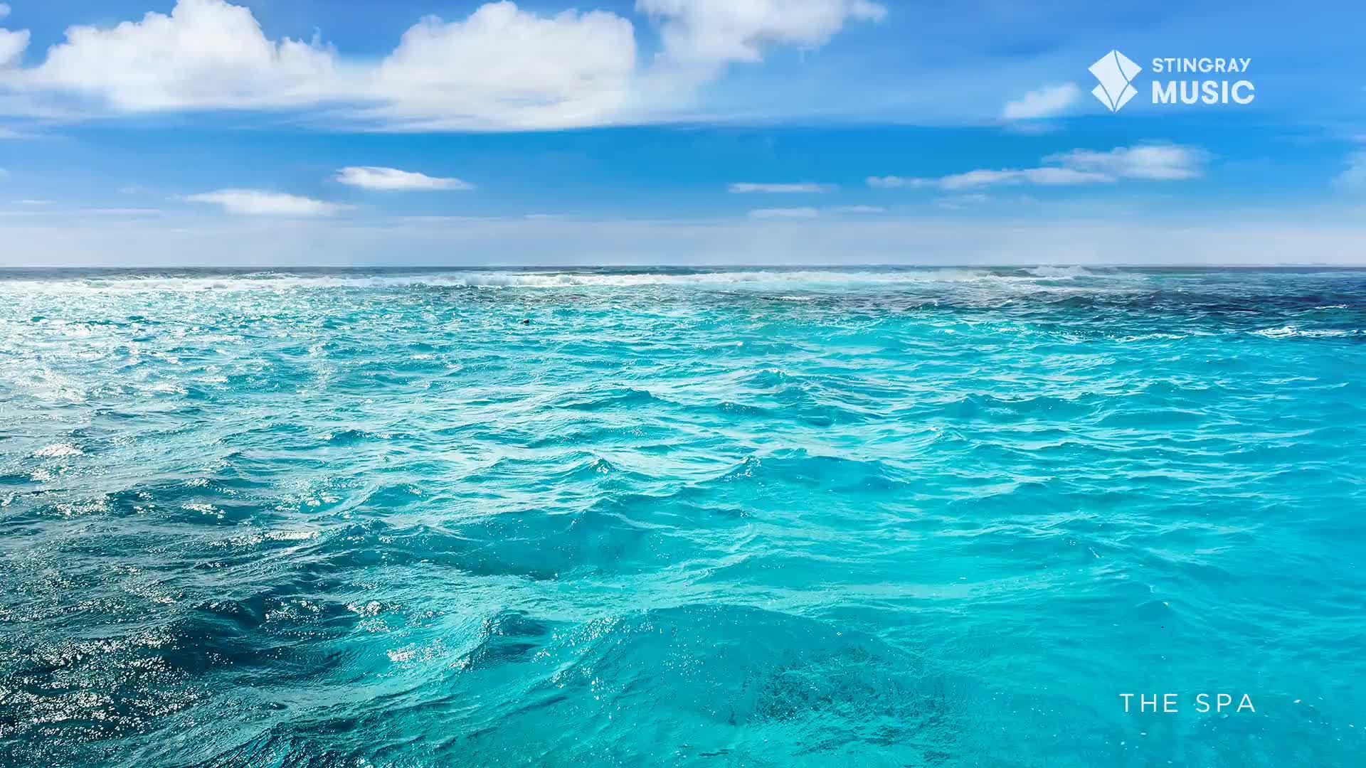 Azure waves undulate gently under a bright sky, the water's surface reflecting the sunlight. The scene, branded by Stingray Music as "The Spa," evokes a sense of calm.
