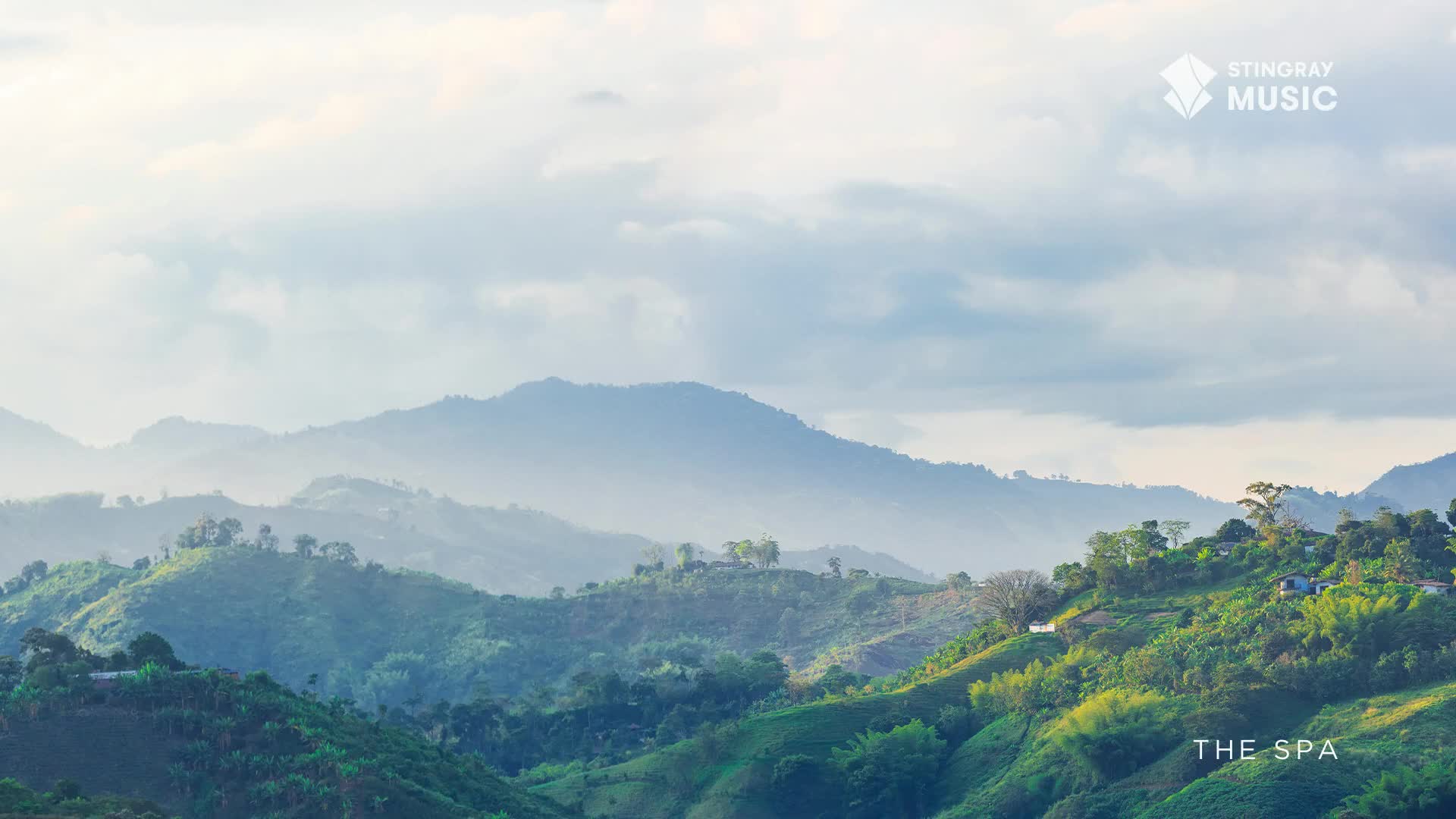 The rolling green hills of Canada stretch out before me, disappearing into a soft blue haze. Tiny structures dot the landscape, nestled amongst the trees, hinting at a peaceful retreat.