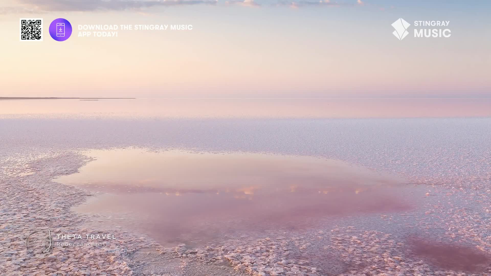The vast expanse of pink salt flats stretches out before me, reflecting the soft pastel sky. A shallow pool of water mirrors the clouds, its surface undisturbed.