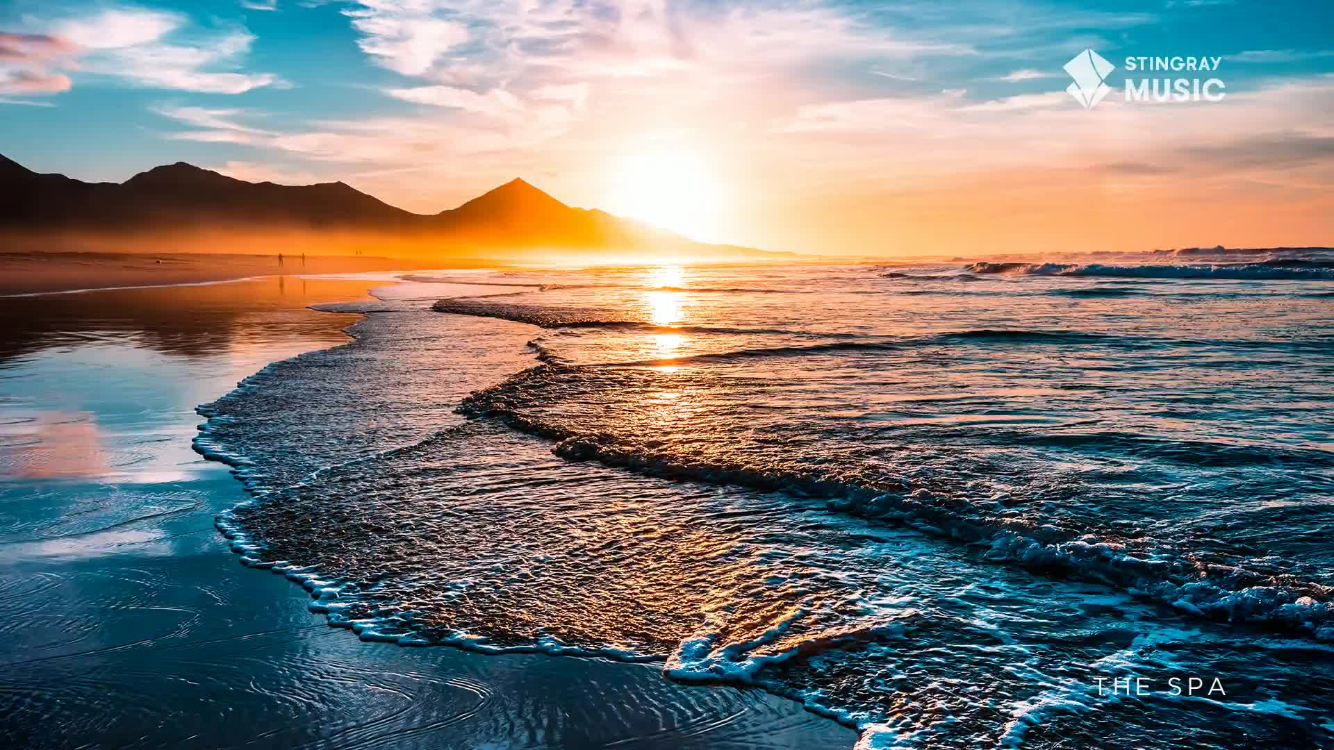 The sun dips behind the mountains, casting a warm glow over the ocean waves rolling onto the shore. A few figures walk along the wet sand, their silhouettes small against the vast expanse. The sun dips behind the mountains, casting a warm glow over the ocean waves rolling onto the shore. A few figures walk along the wet sand, their silhouettes small against the vast expanse.