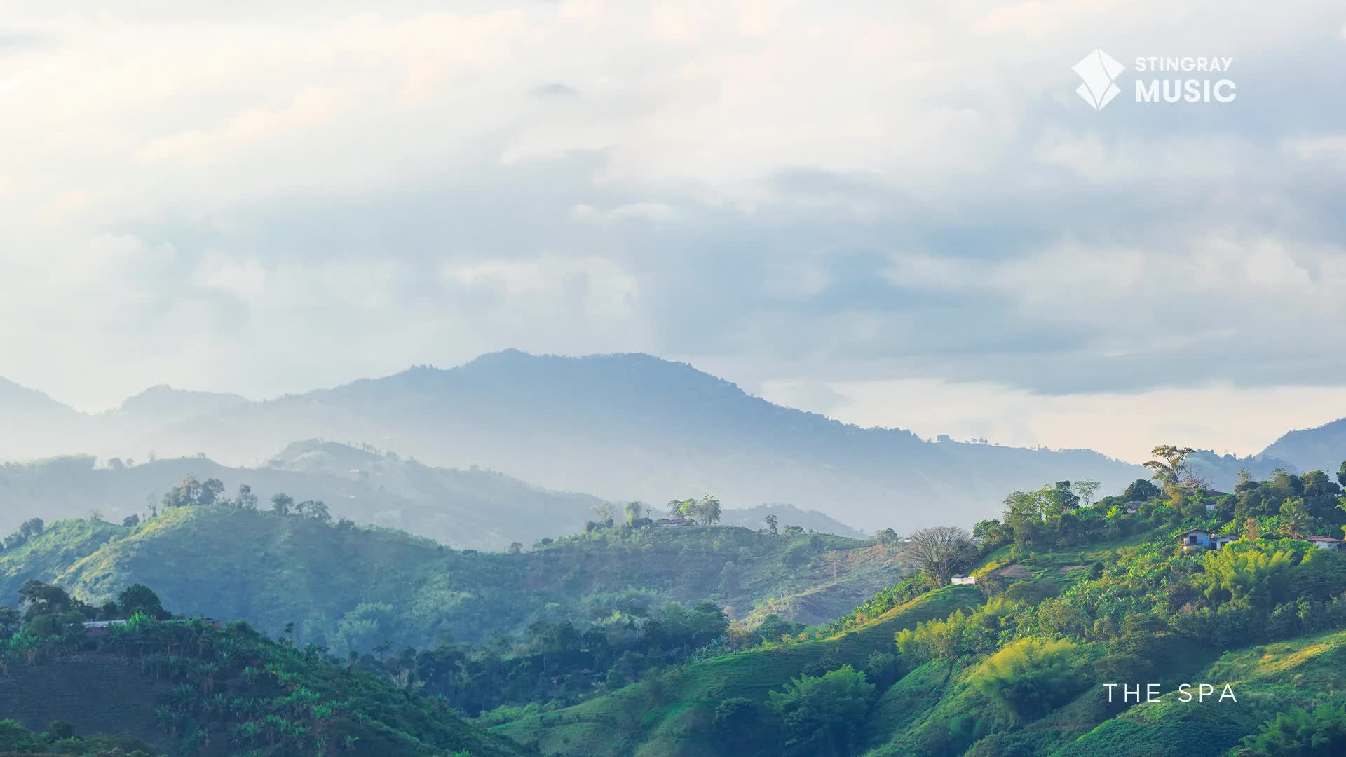 Rolling green hills, dotted with small structures, stretch into a hazy blue distance under a cloudy sky. The air feels still, like the calm before a gentle rain, a perfect setting for a moment of quiet reflection.