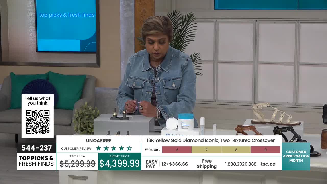 A woman in a denim jacket gestures towards some products on a table, likely demonstrating them for a TSC audience. The screen behind her displays "Top Picks & Fresh Finds" and a QR code.
