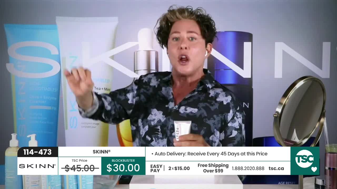 A presenter on TSC is enthusiastically demonstrating a skincare product. He gestures with a small tube while large SKINN bottles stand behind him.