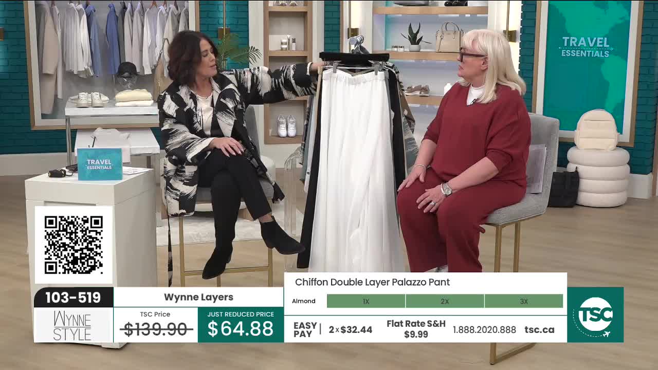 A woman in a black and white patterned jacket gestures towards a pair of flowing white pants. Beside her, another woman in a maroon outfit sits, listening.