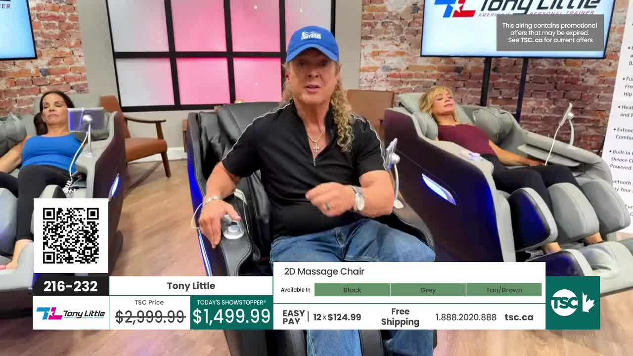 Tony Little is demonstrating a 2D massage chair on TSC, with two women already enjoying the experience. The chair is available in black, grey, and tan/brown.