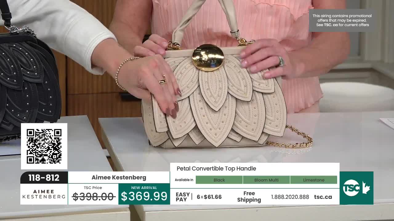 A woman's hands adjust the top handle of a pale beige handbag, its petals dotted with tiny studs. The bag, a new arrival from Aimee Kestenberg, is displayed on a table at TSC.