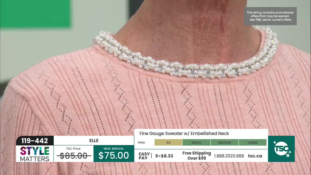 A woman models a pale pink sweater with a delicate pearl and crystal embellishment around the neckline. The sweater features a subtle diamond pattern knit throughout, and the TSC logo appears in the corner.