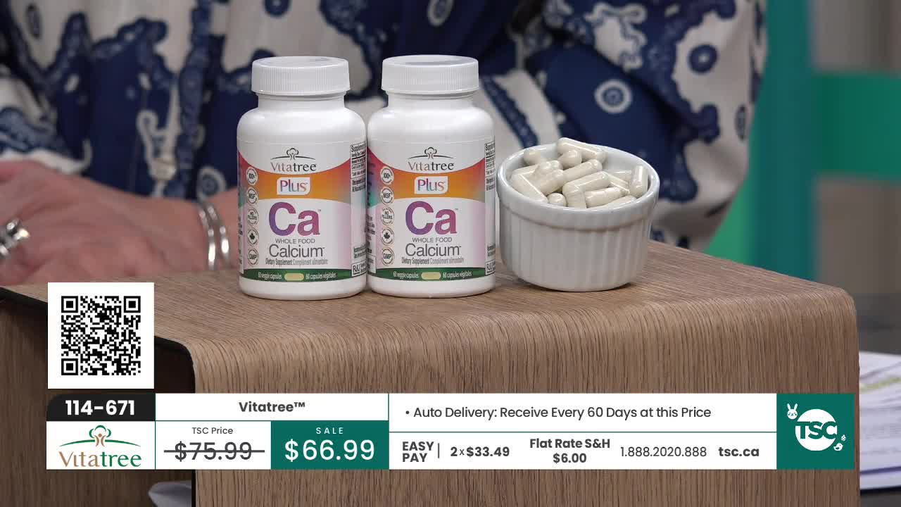 Two bottles of Vitatre Plus Ca sit on a wooden stand, next to a small white dish overflowing with capsules. The television screen displays the product name and price, along with a QR code.