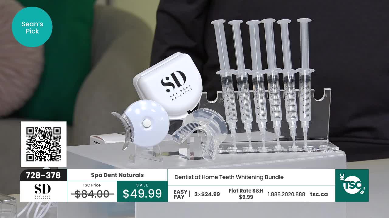 A row of six syringes filled with clear gel stands upright in a clear rack. Beside them, a white case with "SD" printed on it sits next to a mouthguard and a small, round device with a light. This is the Spa Dent Naturals Dentist at Home Teeth Whitening Bundle, currently on sale for $49.99 on TSC.