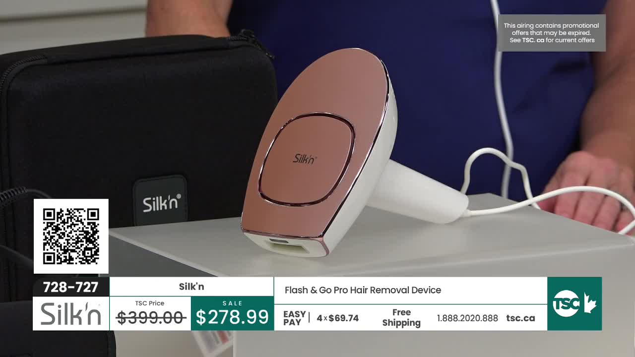 A rose gold hair removal device sits on a white stand, its cord trailing to the right. Beside it, a black Silk'n case rests on a surface. A rose gold hair removal device sits on a white stand, its cord trailing to the right. Beside it, a black Silk'n case rests on a surface.