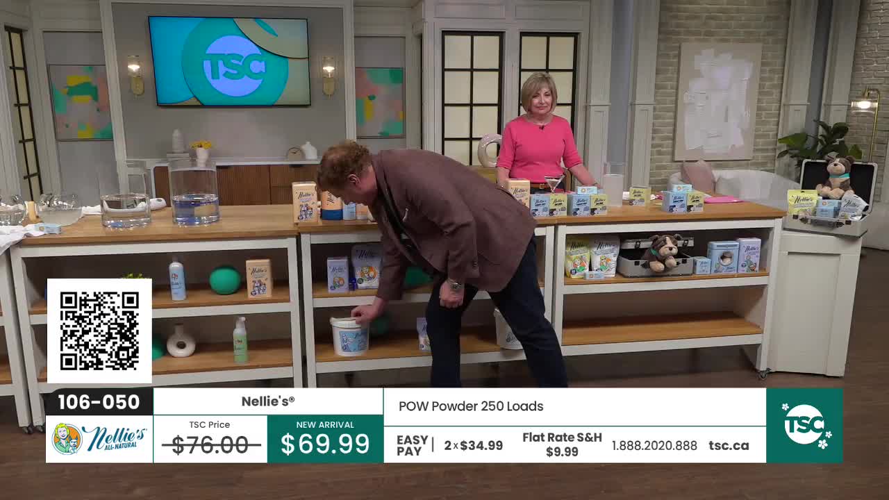 A man in a brown jacket bends down to pick up a white tub from a shelf. Behind him, a woman in a pink shirt stands by a counter displaying various products. A man in a brown jacket bends down to pick up a white tub from a shelf. Behind him, a woman in a pink shirt stands by a counter displaying various products.