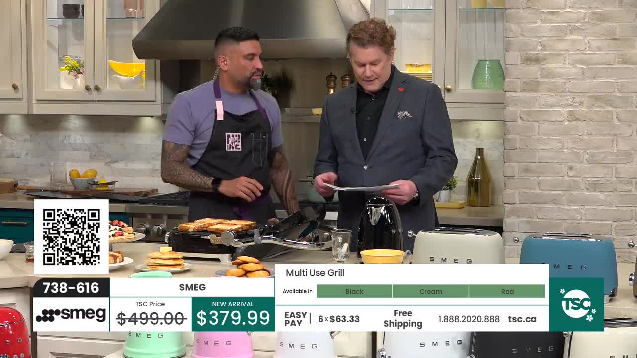 Two men stand in a bright kitchen, one demonstrating a grill while the other reads from a paper. A selection of colorful toasters sits on the counter beside them. Two men stand in a bright kitchen, one demonstrating a grill while the other reads from a paper. A selection of colorful toasters sits on the counter beside them.