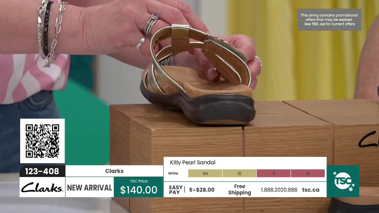 A hand adjusts the straps of a gold sandal resting on a wooden block. The TSC logo and product details are displayed on screen. A hand adjusts the straps of a gold sandal resting on a wooden block. The TSC logo and product details are displayed on screen.