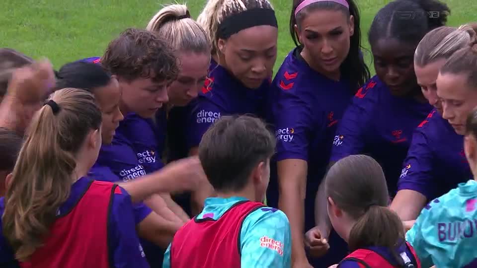 The team huddles together, their hands clasped in the center. They're all looking down, locked in a moment of focus before the game.
