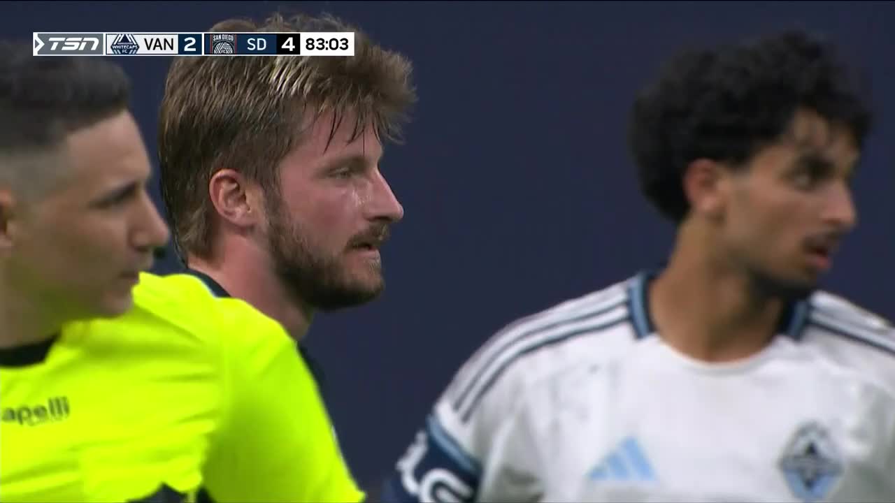 The Vancouver player, drenched in sweat, stares intently at something out of frame. A San Diego player looks on, while the score on TSN5 shows the visitors leading late in the game.
