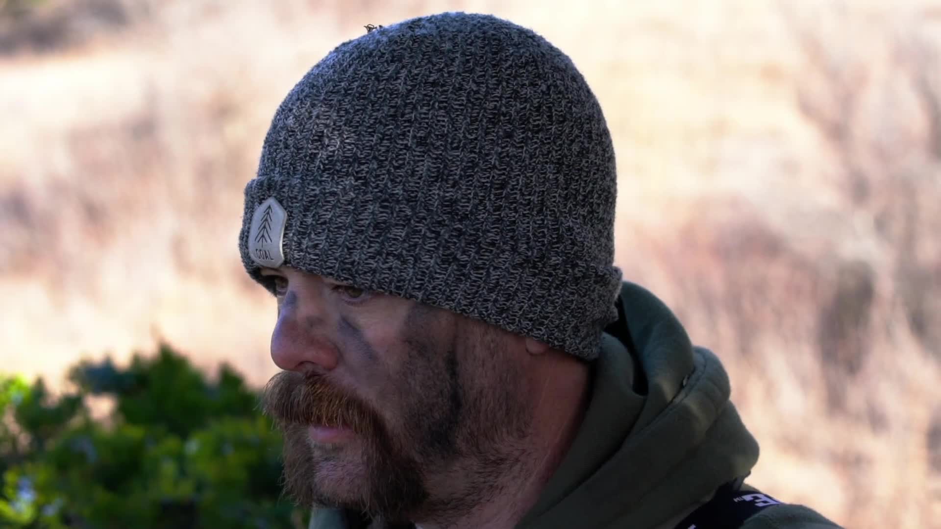 A man with camouflage paint on his face and a toque watches intently. He appears to be on the lookout for something in the Canadian wilderness. A man with camouflage paint on his face and a toque watches intently. He appears to be on the lookout for something in the Canadian wilderness.