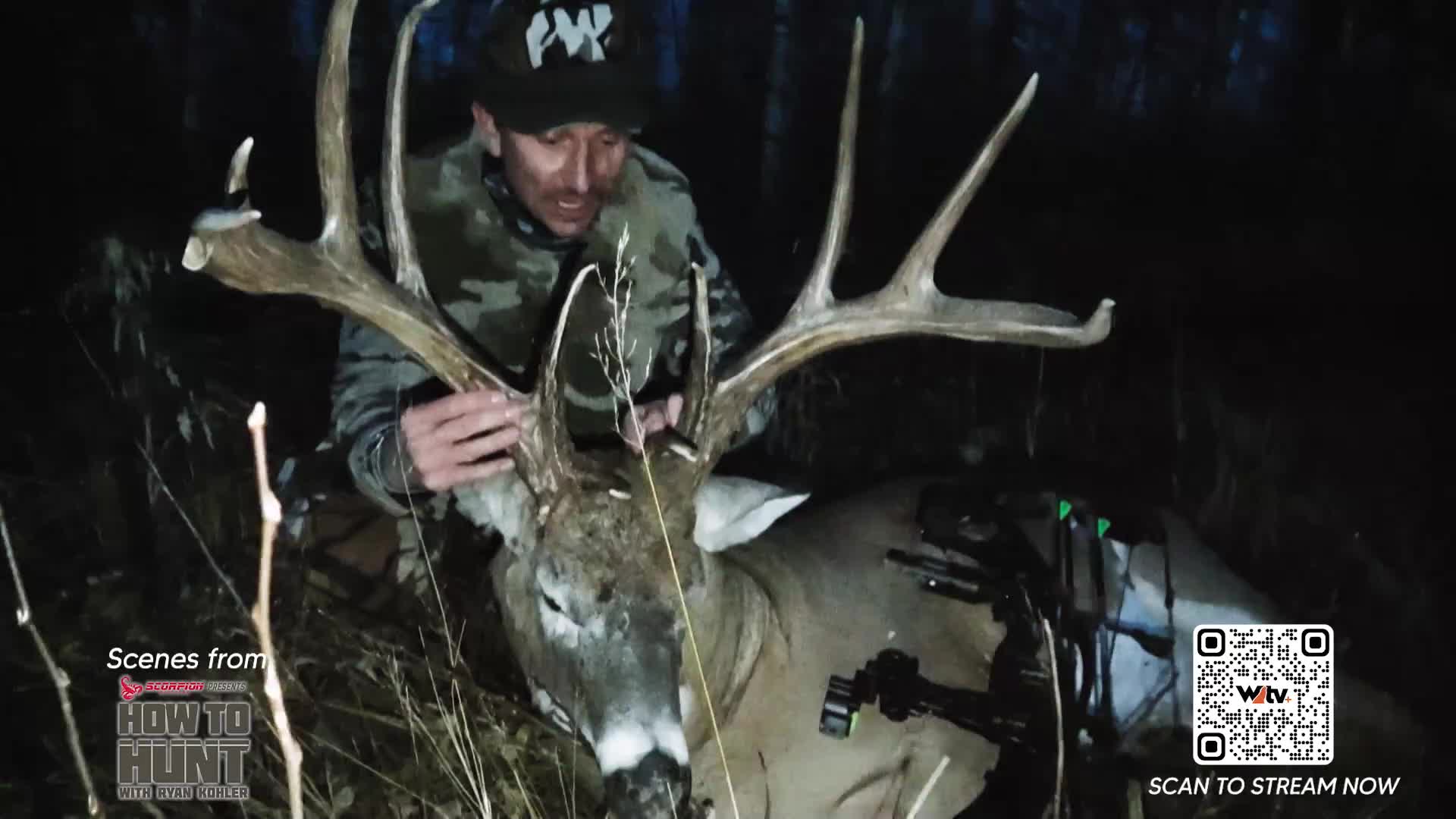 A hunter kneels beside a massive buck, its impressive antlers reaching skyward. The scene, likely from a Canadian hunt featured on Wild TV, captures a moment of triumph in the dim light. A hunter kneels beside a massive buck, its impressive antlers reaching skyward. The scene, likely from a Canadian hunt featured on Wild TV, captures a moment of triumph in the dim light.
