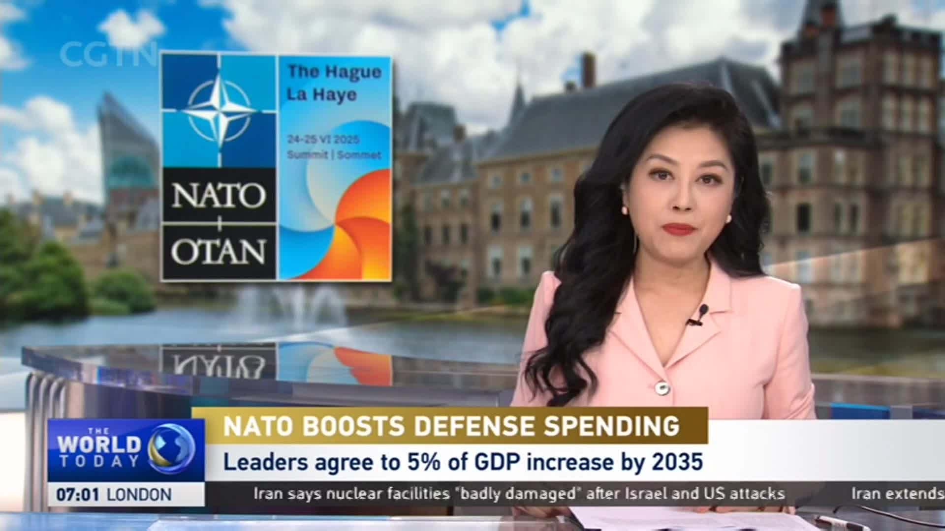 A woman in a pink blazer is speaking directly to the camera, with a news graphic about NATO's defense spending displayed below her. Behind her, the backdrop shows a body of water and a building, likely in The Hague, as indicated by the CGTN graphic.
