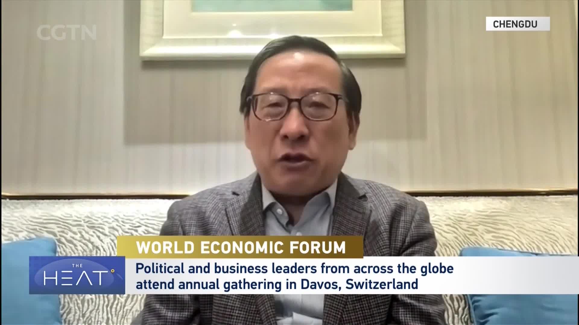 A man in a suit speaks directly to the camera, his glasses reflecting the light. CGTN's "The Heat" graphic overlays the bottom of the screen, identifying the World Economic Forum's annual gathering in Davos.