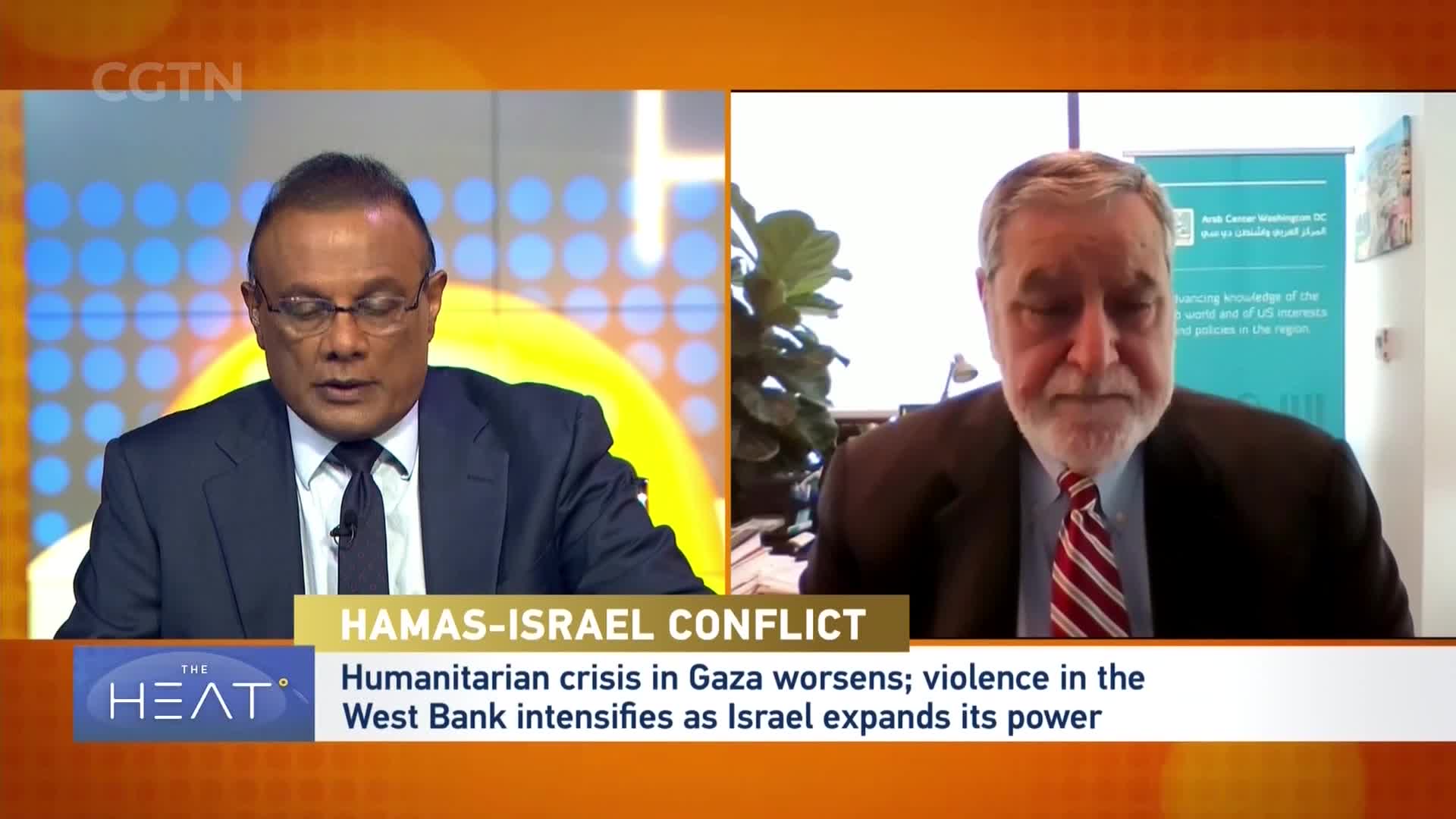 A man in a suit and tie speaks on a screen, his face framed by a large plant. Below him, text on a CGTN broadcast announces the "Hamas-Israel Conflict" and a worsening humanitarian crisis in Gaza. A man in a suit and tie speaks on a screen, his face framed by a large plant. Below him, text on a CGTN broadcast announces the "Hamas-Israel Conflict" and a worsening humanitarian crisis in Gaza.