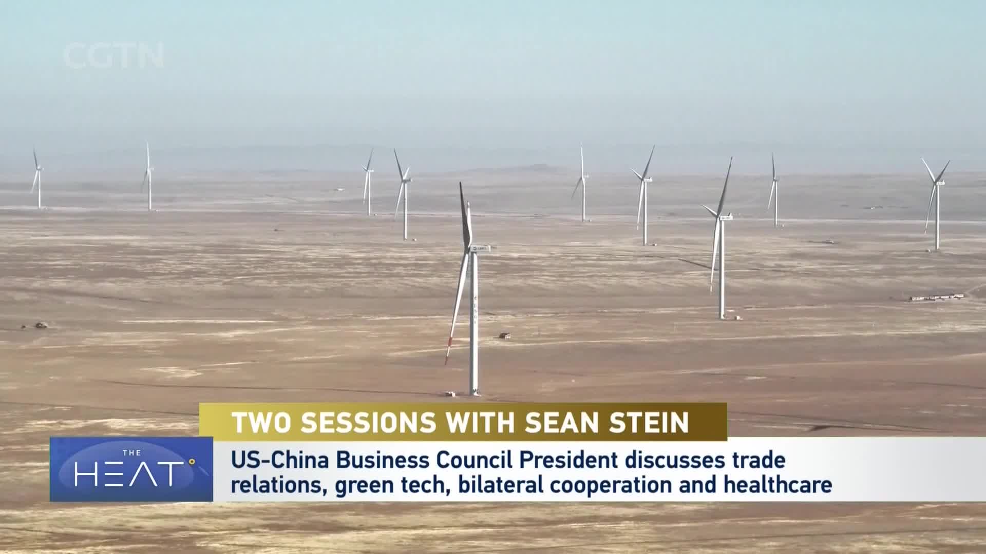 Wind turbines stand tall against a hazy sky in a vast, arid landscape. Their blades slowly turn, catching the breeze in this part of China.