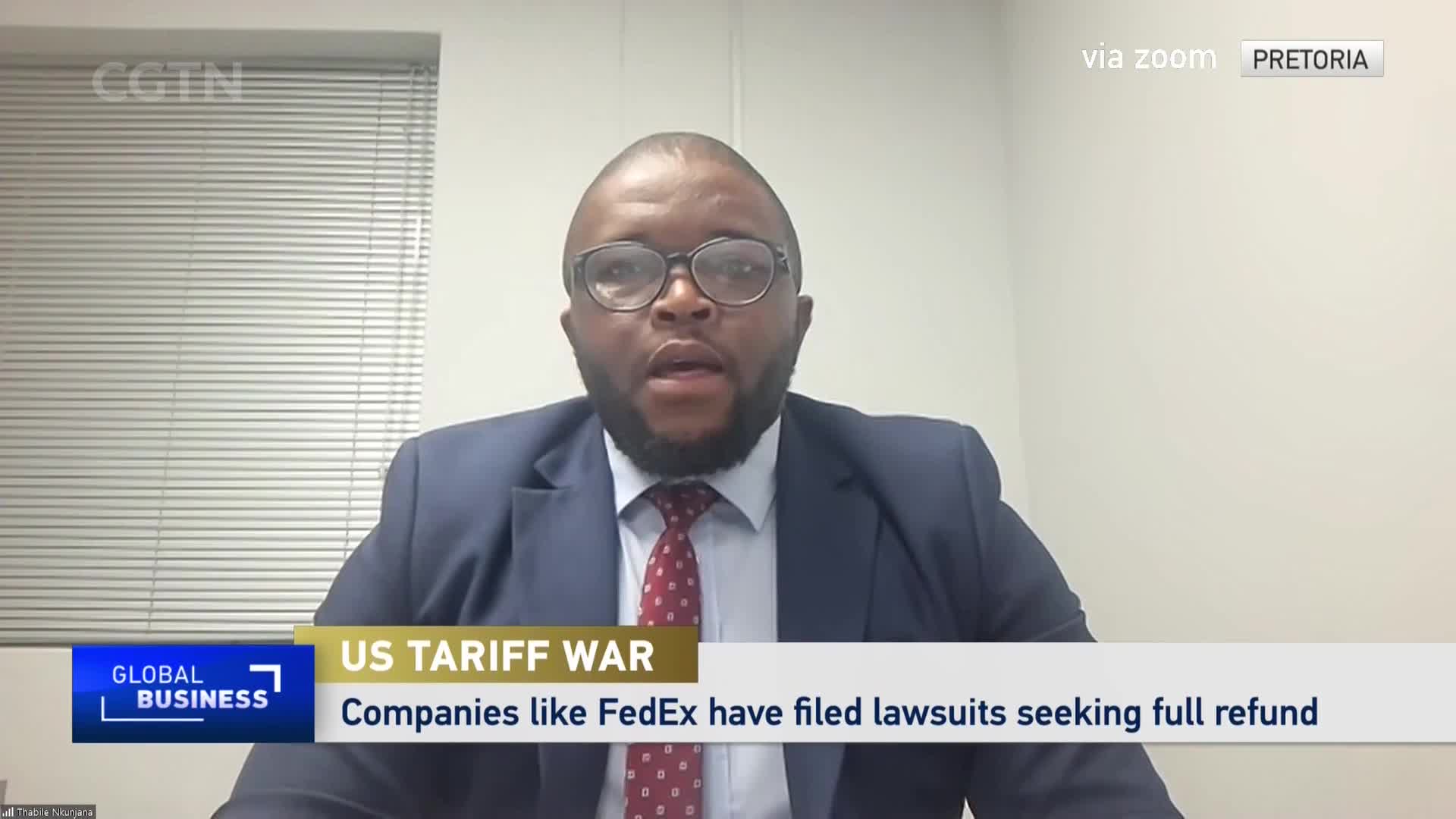 A man in a suit and tie speaks on a video call, his face framed by glasses. A graphic overlay from CGTN's "Global Business" segment announces "US Tariff War" and details lawsuits seeking refunds.