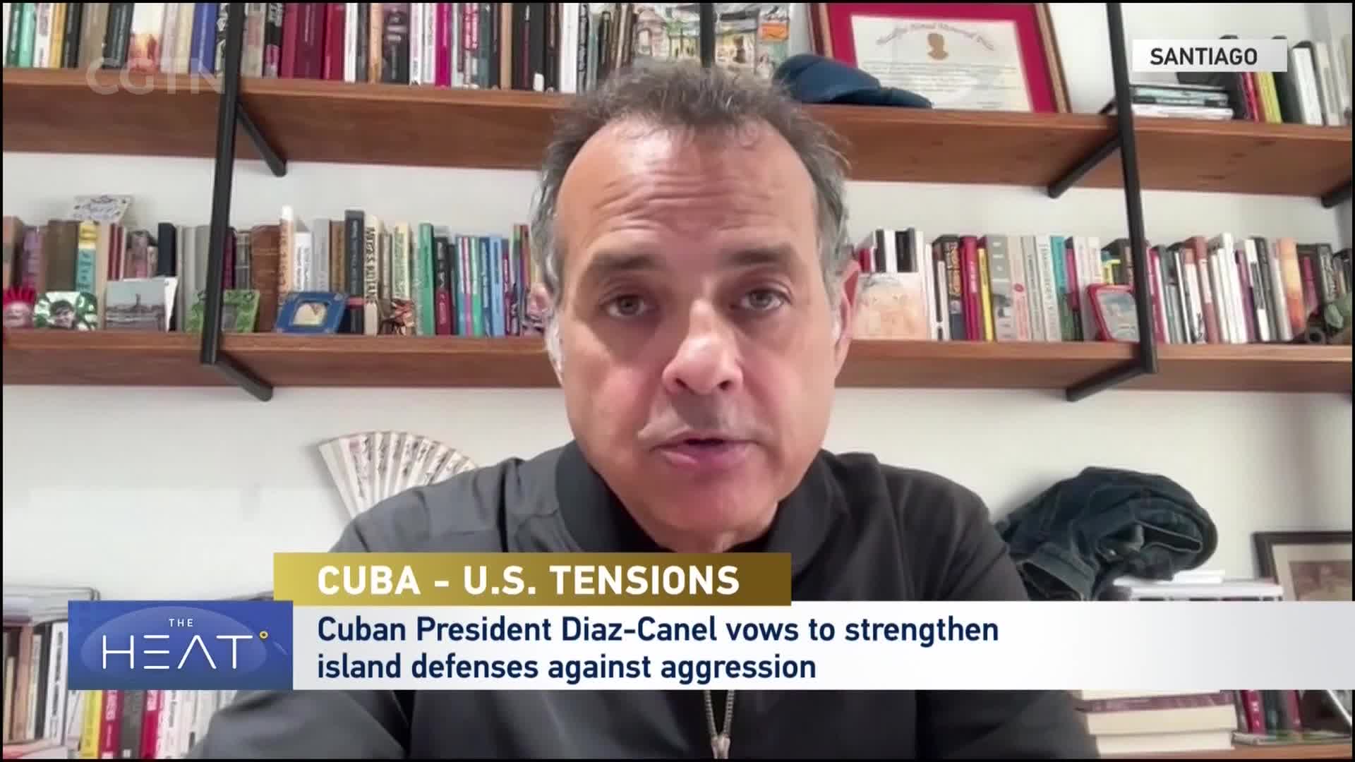 A man speaks directly to the camera, his face filling the frame. Behind him, bookshelves are packed with titles, and a CGTN banner indicates the broadcast is from China.