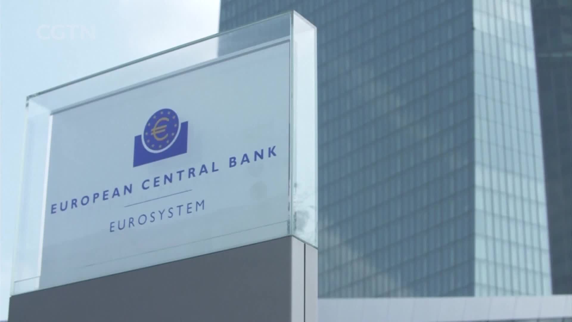 A glass sign displays "EUROPEAN CENTRAL BANK EUROSYSTEM" with the Euro symbol. Behind it, a modern skyscraper with a grid of windows rises into the sky.
