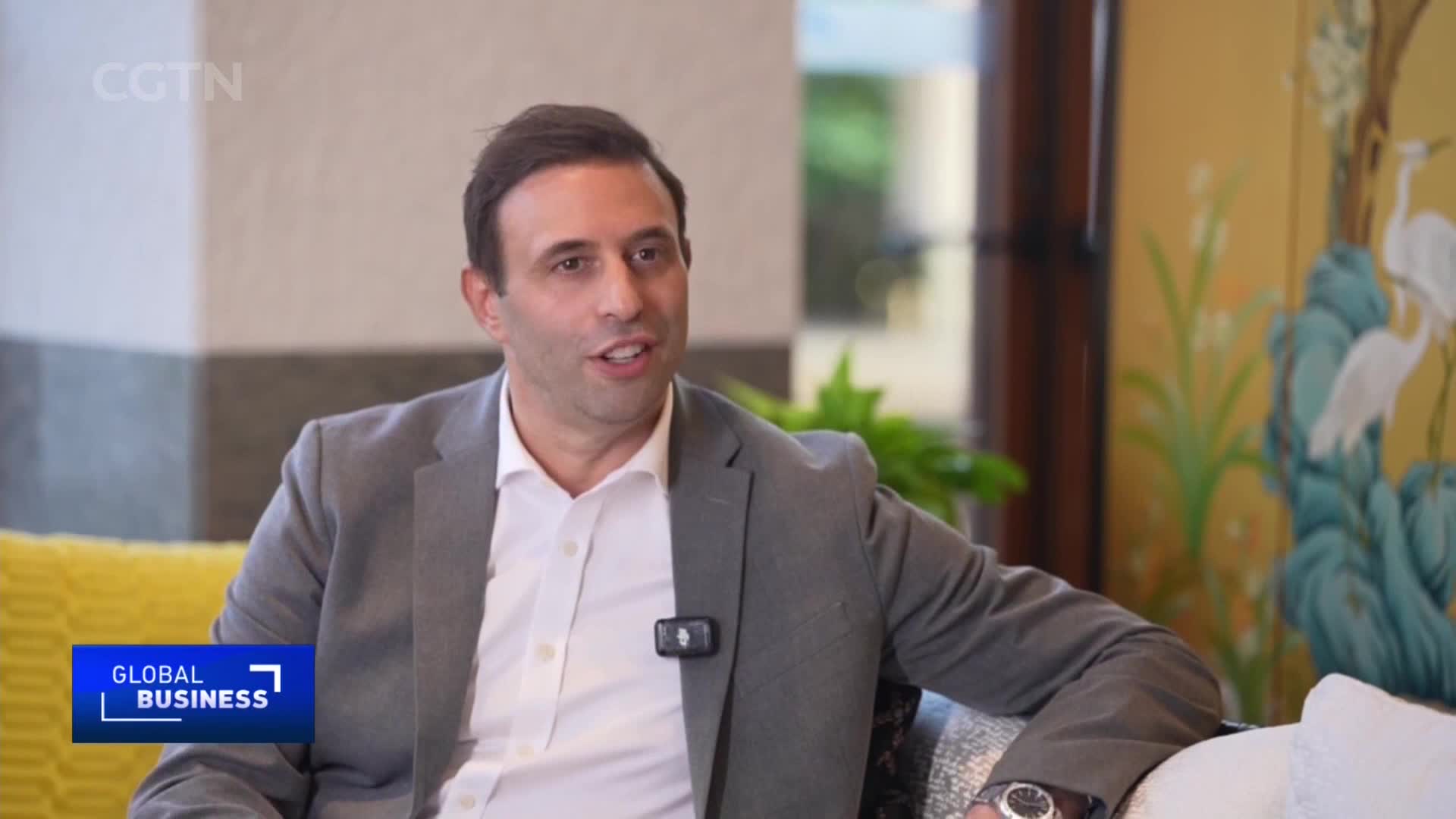 A man in a suit speaks, a small microphone clipped to his lapel. The CGTN "Global Business" logo appears in the lower left corner, hinting at a broadcast from China.