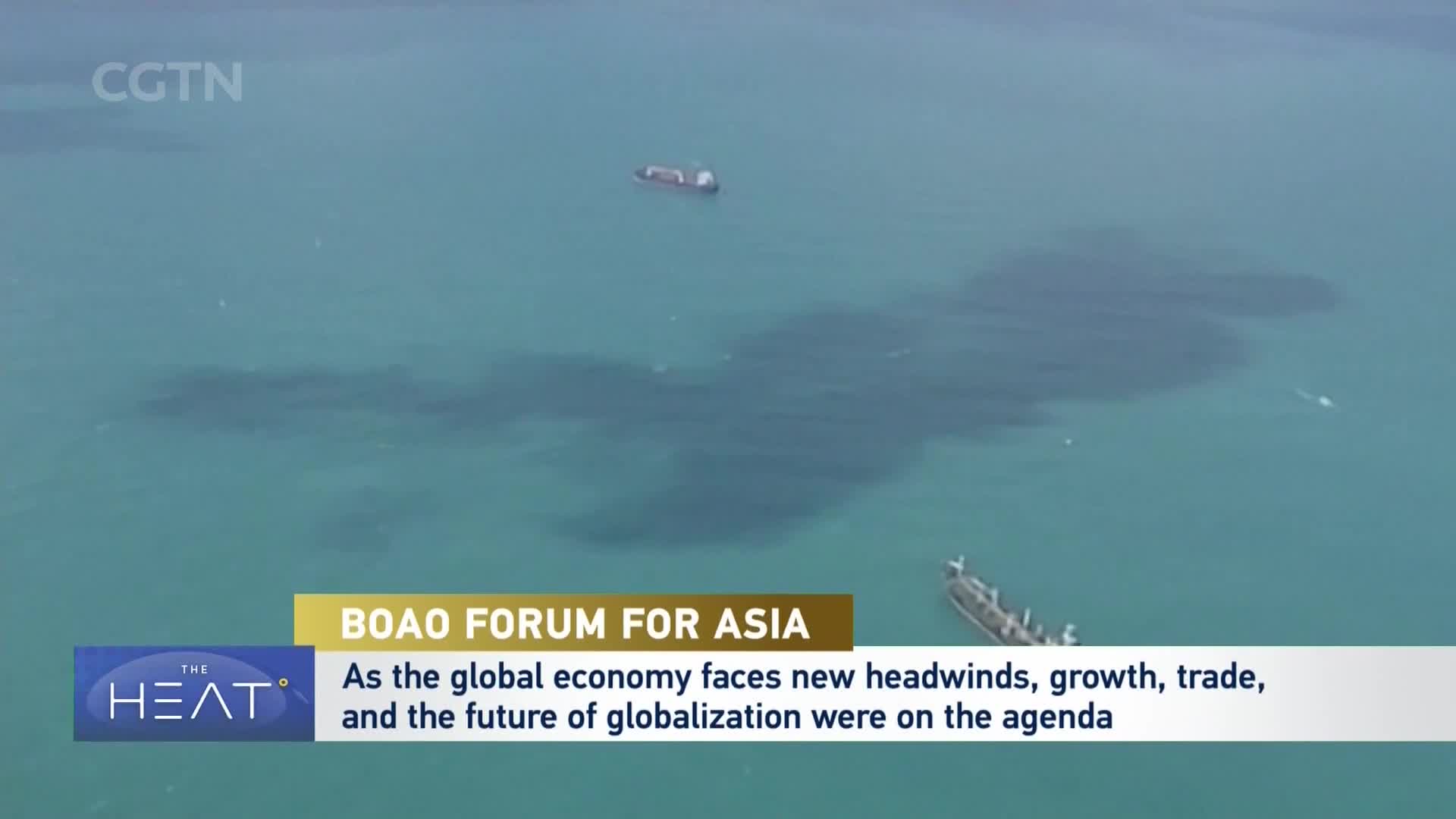 A large cargo ship moves slowly across the turquoise water. Another vessel, smaller and closer to shore, is anchored.