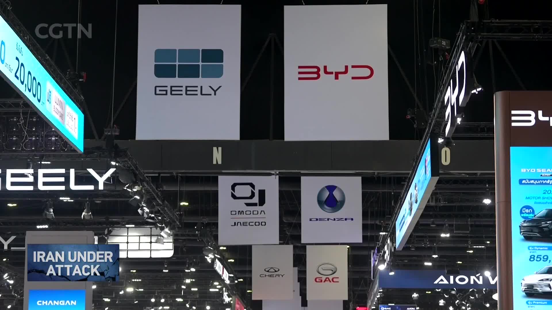 Giant white banners with the Geely and BYD logos hang high above. Below them, smaller banners display logos for Omoda, Jaecoo, Denza, Chery, and GAC. Giant white banners with the Geely and BYD logos hang high above. Below them, smaller banners display logos for Omoda, Jaecoo, Denza, Chery, and GAC.
