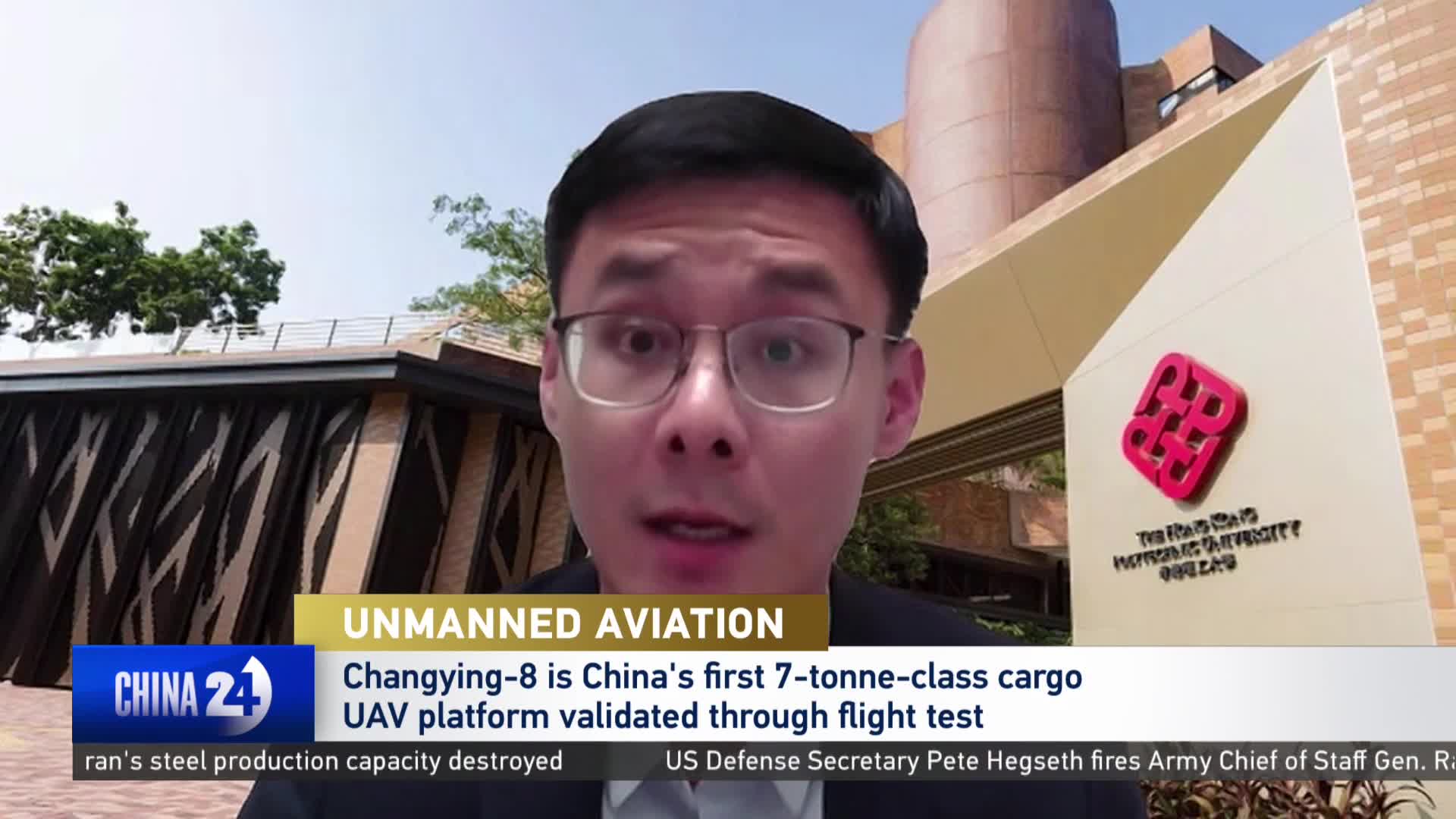 A man in glasses is speaking, with a building behind him featuring a red logo. A news ticker scrolls below, reporting on China's Changying-8 cargo UAV. A man in glasses is speaking, with a building behind him featuring a red logo. A news ticker scrolls below, reporting on China's Changying-8 cargo UAV.