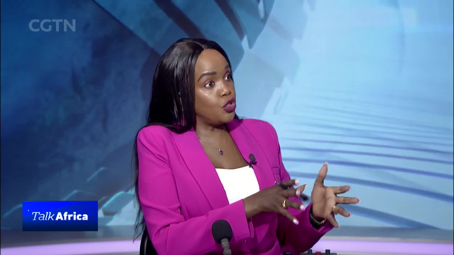 A woman in a bright pink blazer speaks animatedly, her hands gesturing. The CGTN logo and "Talk Africa" graphic appear on screen.
