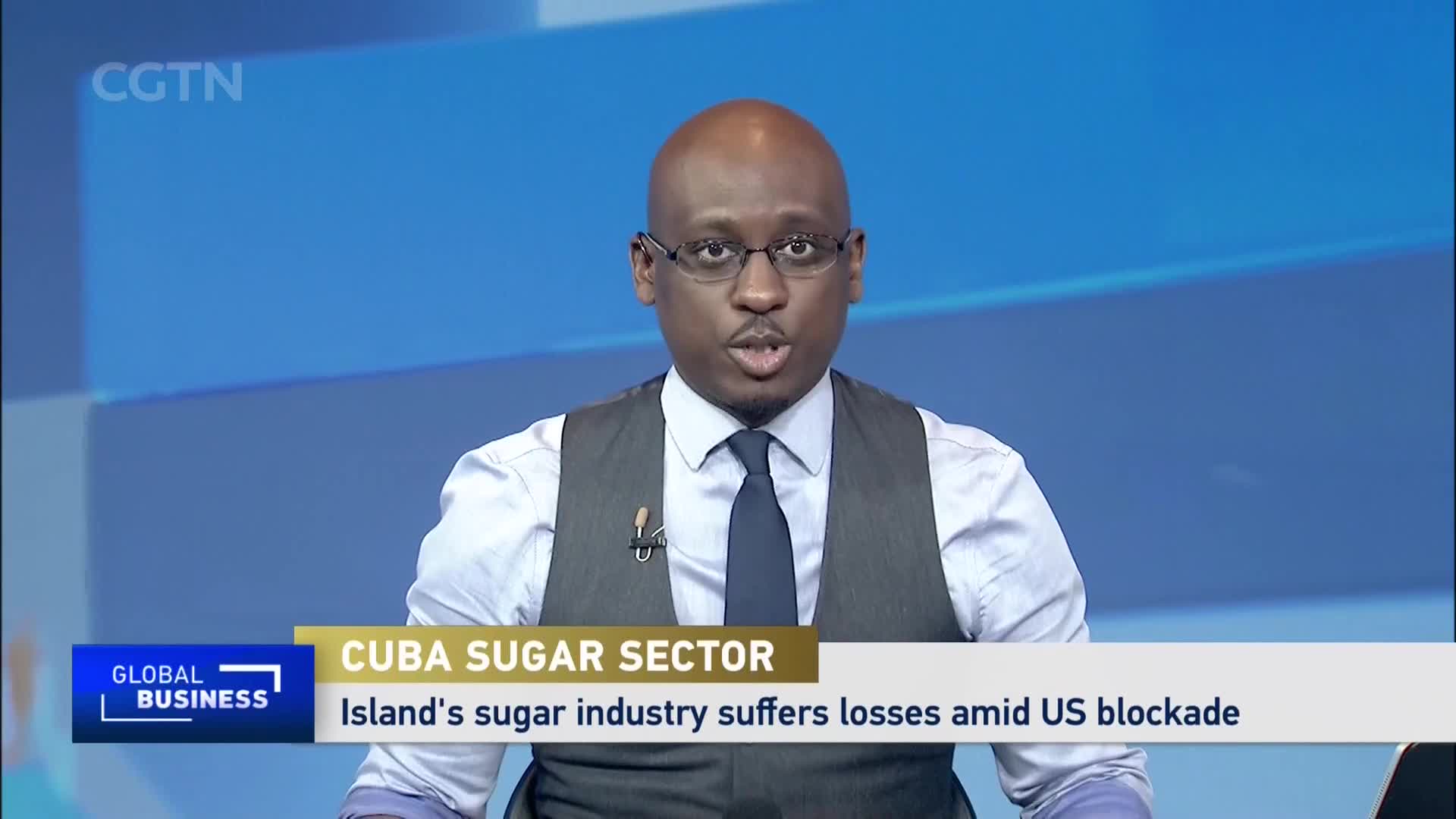 A man in a vest and tie speaks directly to the camera, his words about Cuba's sugar sector and US blockade filling the screen. The CGTN logo is visible in the upper left corner.